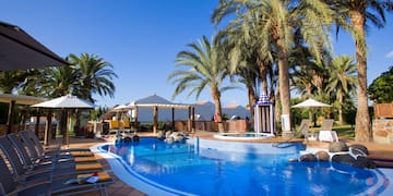 a pool with palm trees and umbrellas