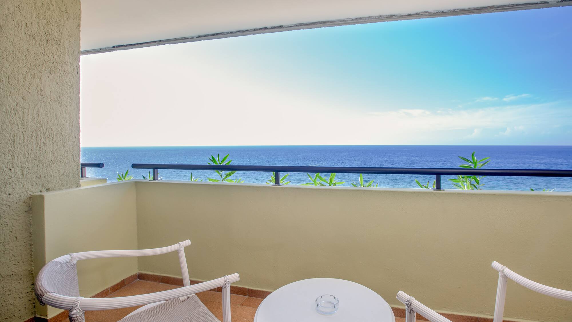 a balcony with a table and chairs overlooking the ocean