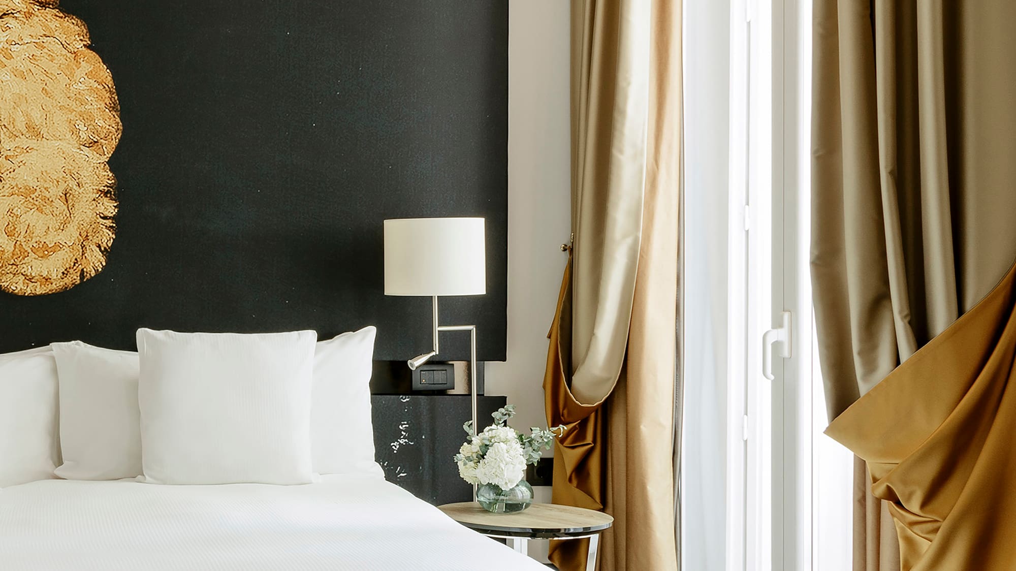 a bed with white sheets and a lamp next to a window