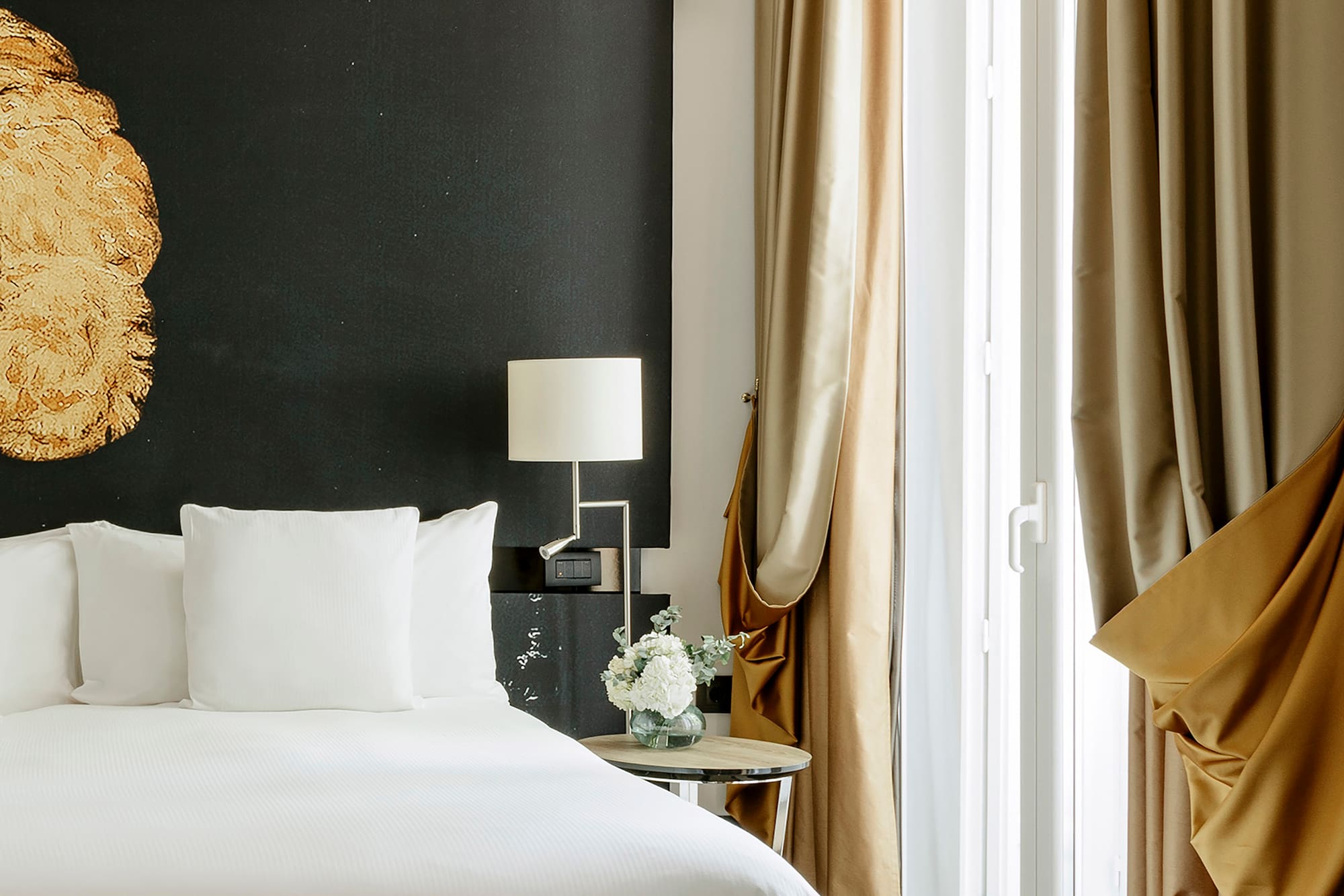 a bed with white sheets and a lamp next to a window