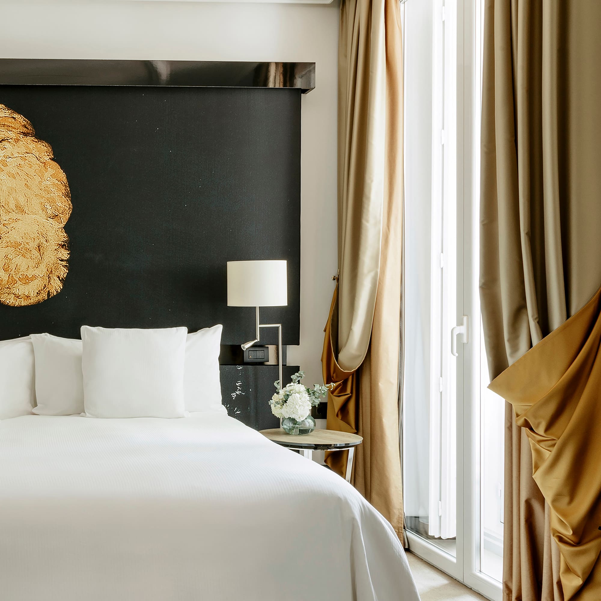 a bed with white sheets and a lamp next to a window