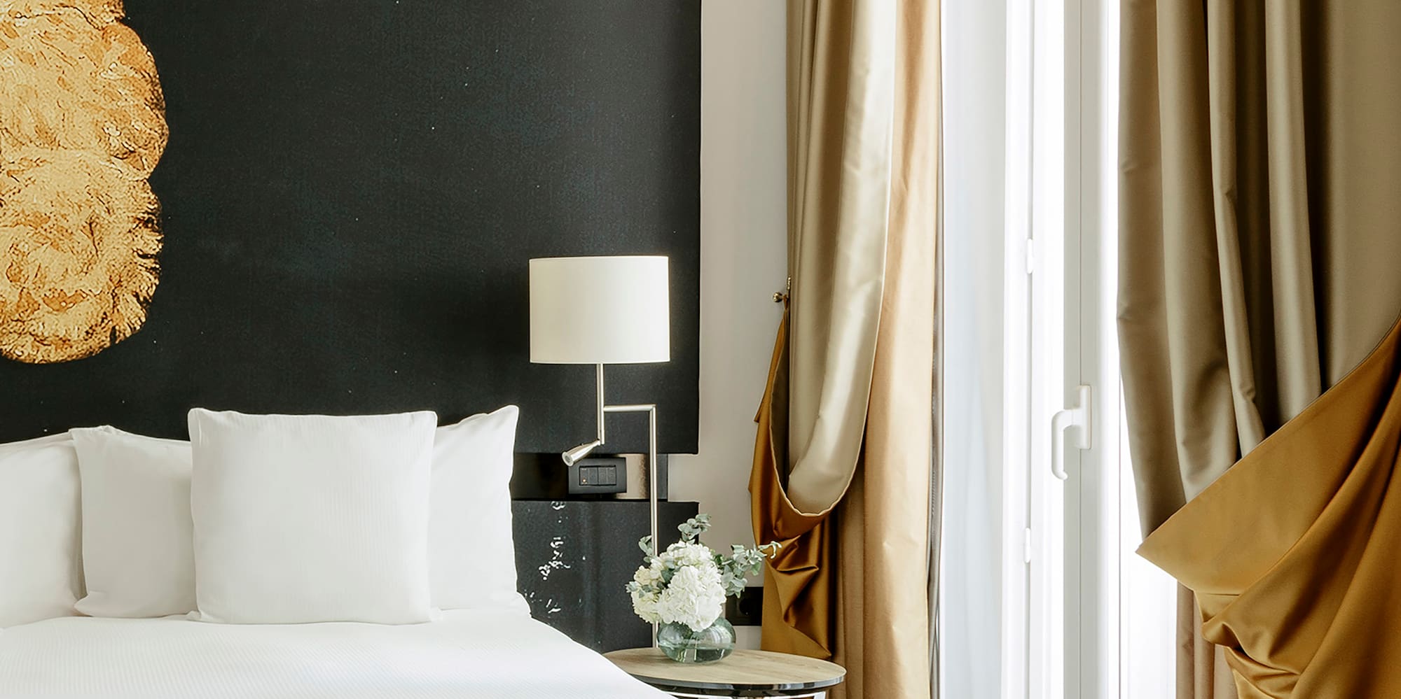 a bed with white sheets and a lamp next to a window