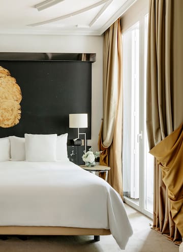 a bed with white sheets and a lamp next to a window