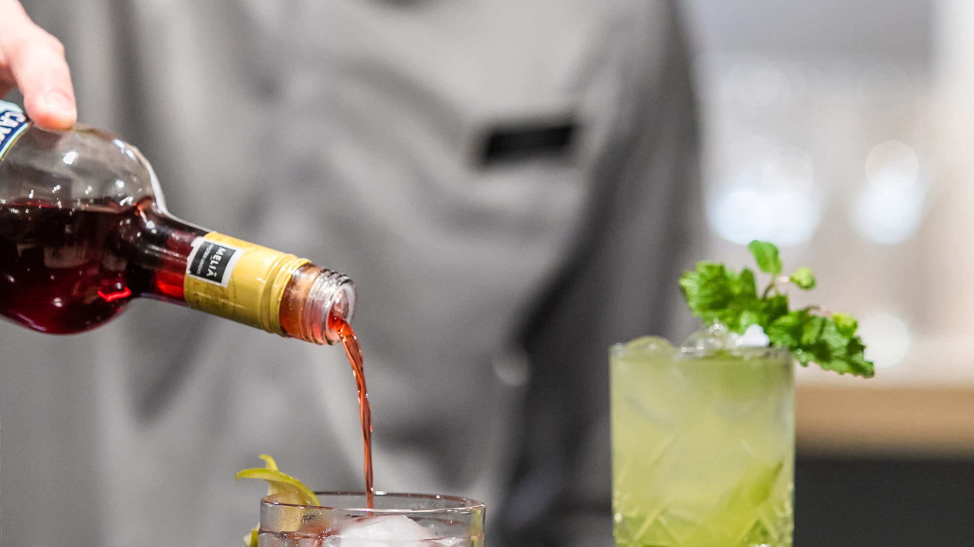 a person pouring a drink into a glass