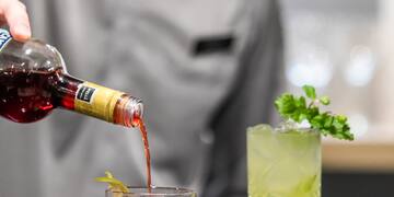 a person pouring a drink into a glass
