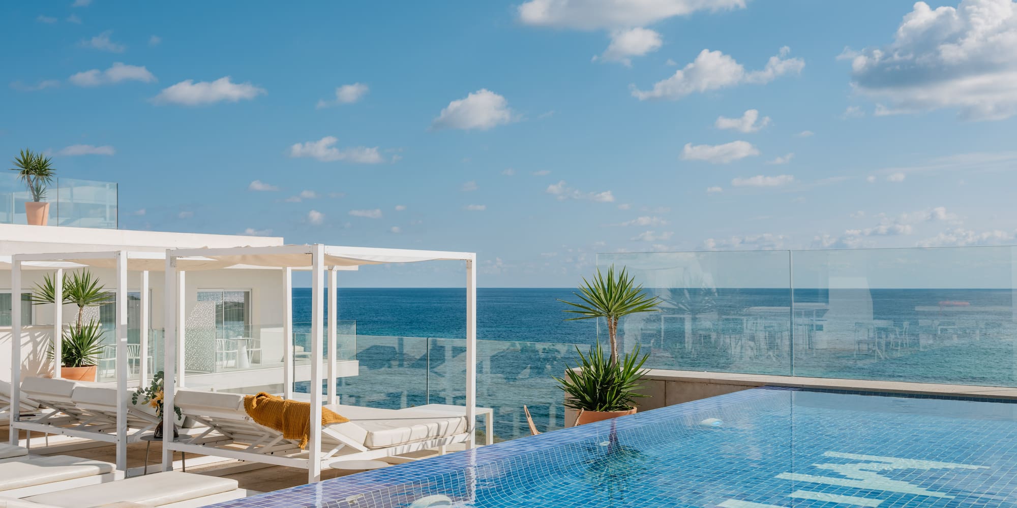 a pool with a deck chair and a glass railing overlooking the ocean