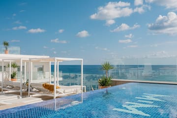a pool with a deck chair and a glass railing overlooking the ocean