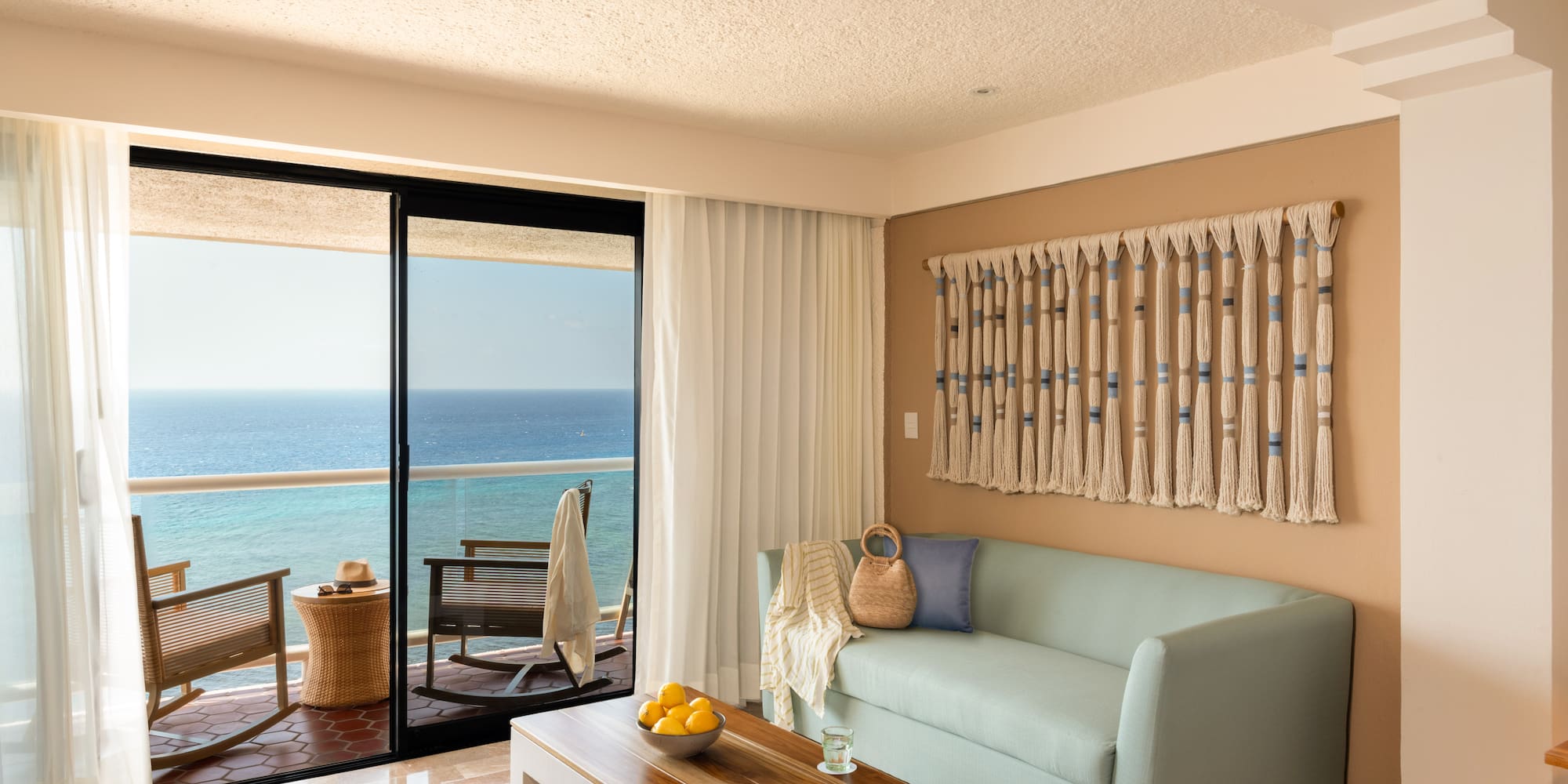Ocean view living room with light blue sofa, balcony, and coastal decor.