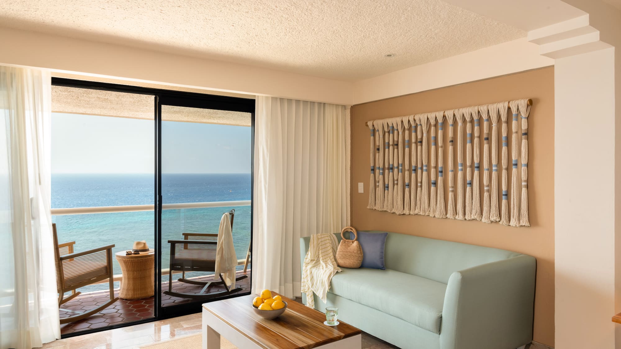 Ocean view living room with light blue sofa, balcony, and coastal decor.