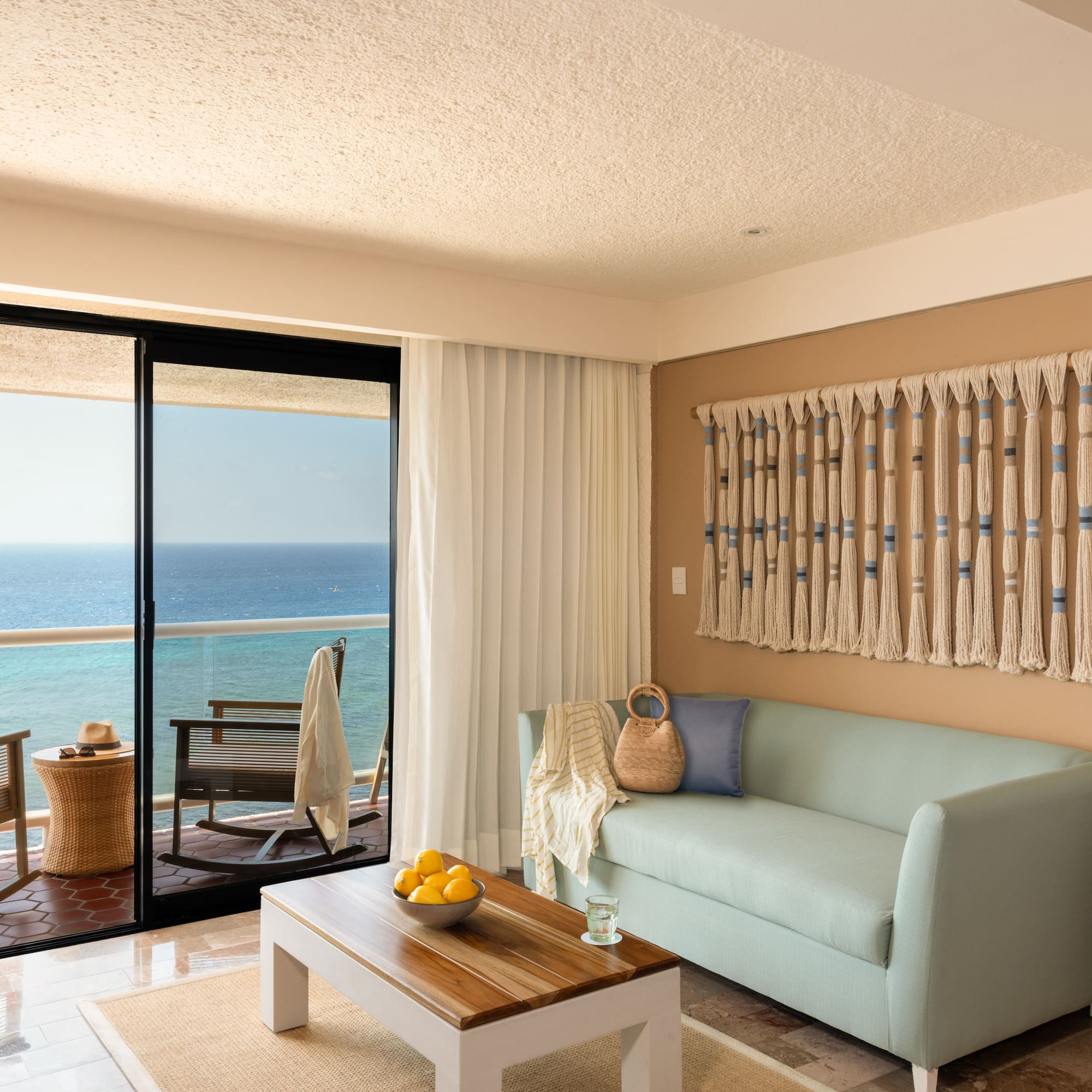 Ocean view living room with light blue sofa, balcony, and coastal decor.