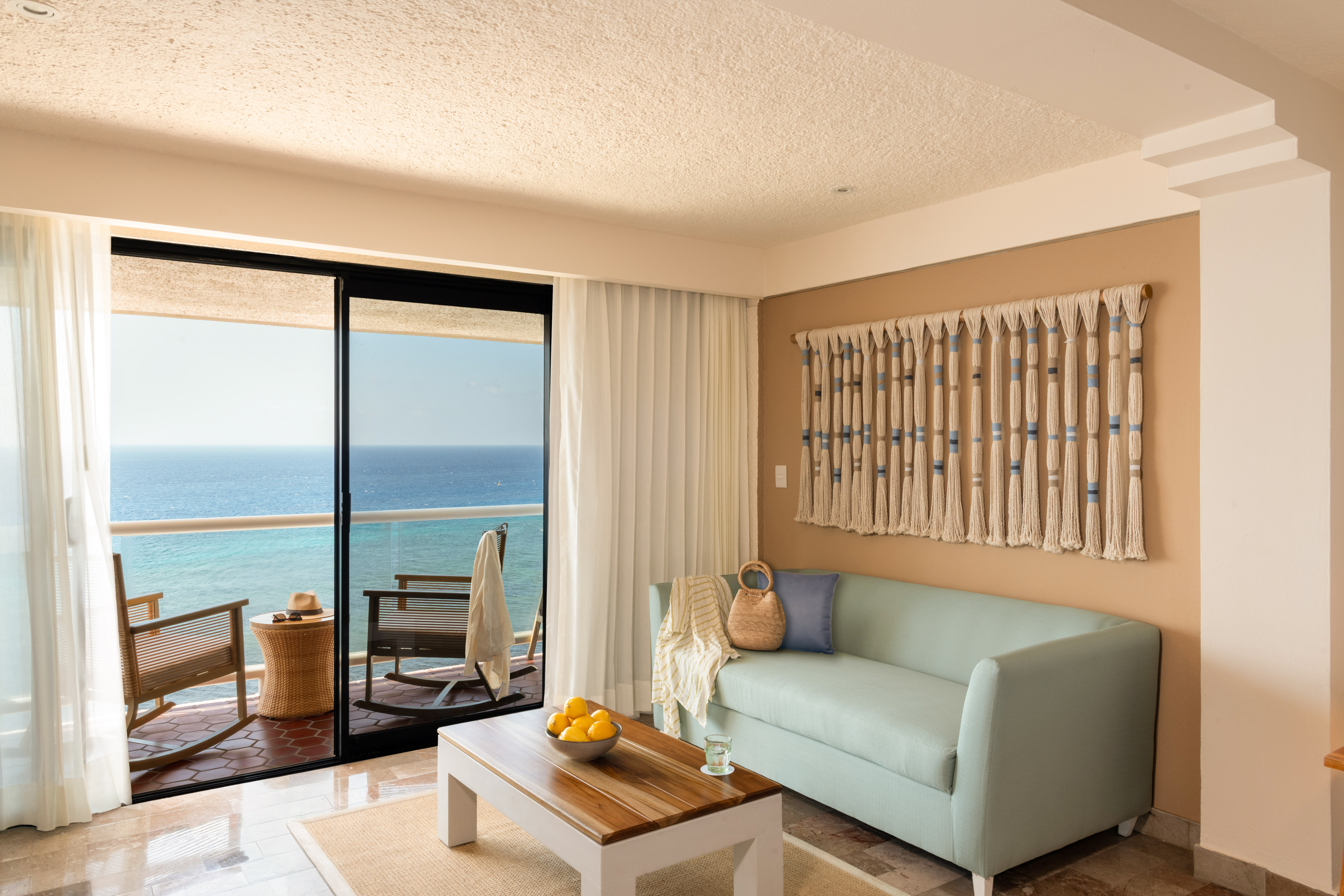 Ocean view living room with light blue sofa, balcony, and coastal decor.