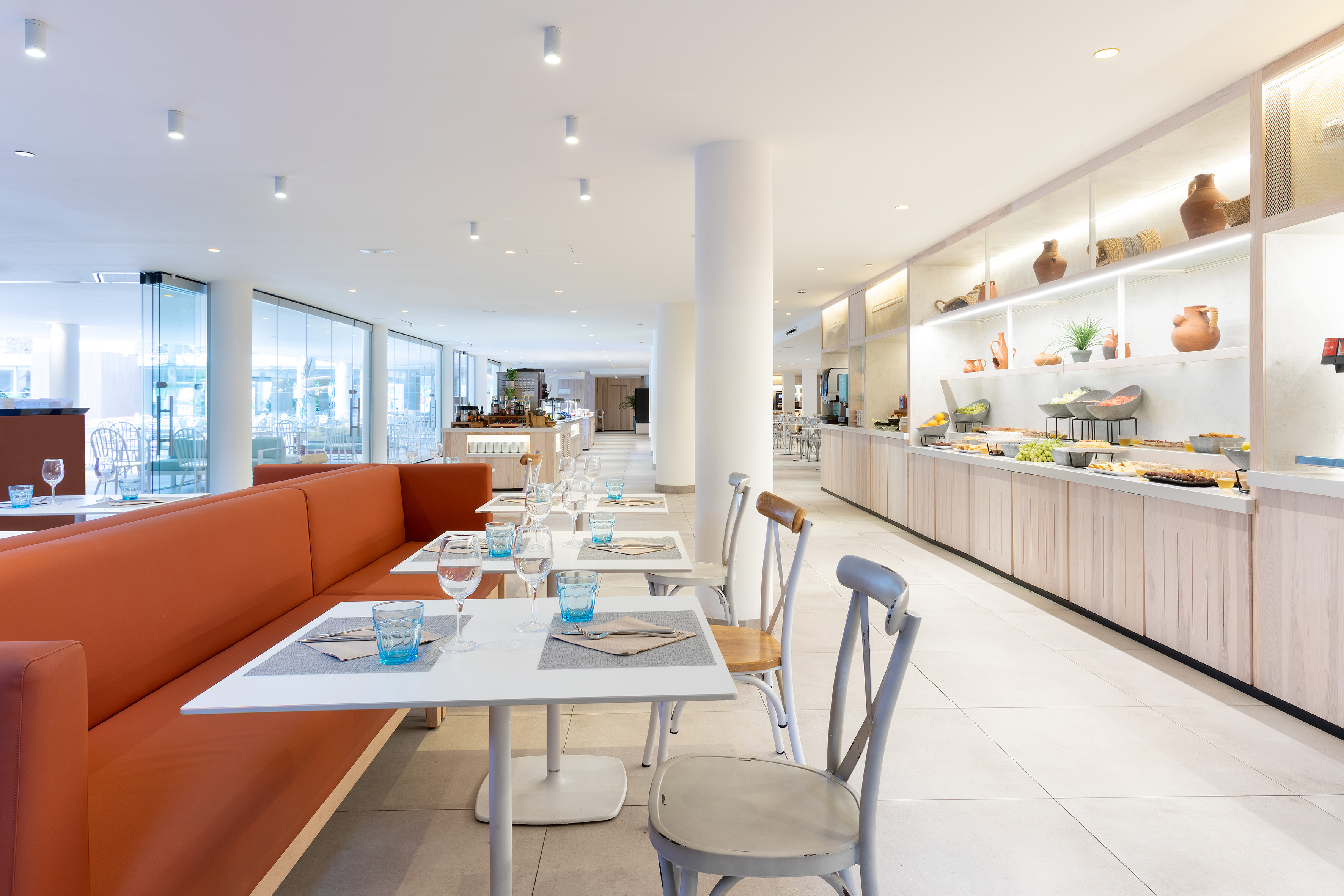 Bright modern buffet restaurant with orange banquette seating and glass windows.