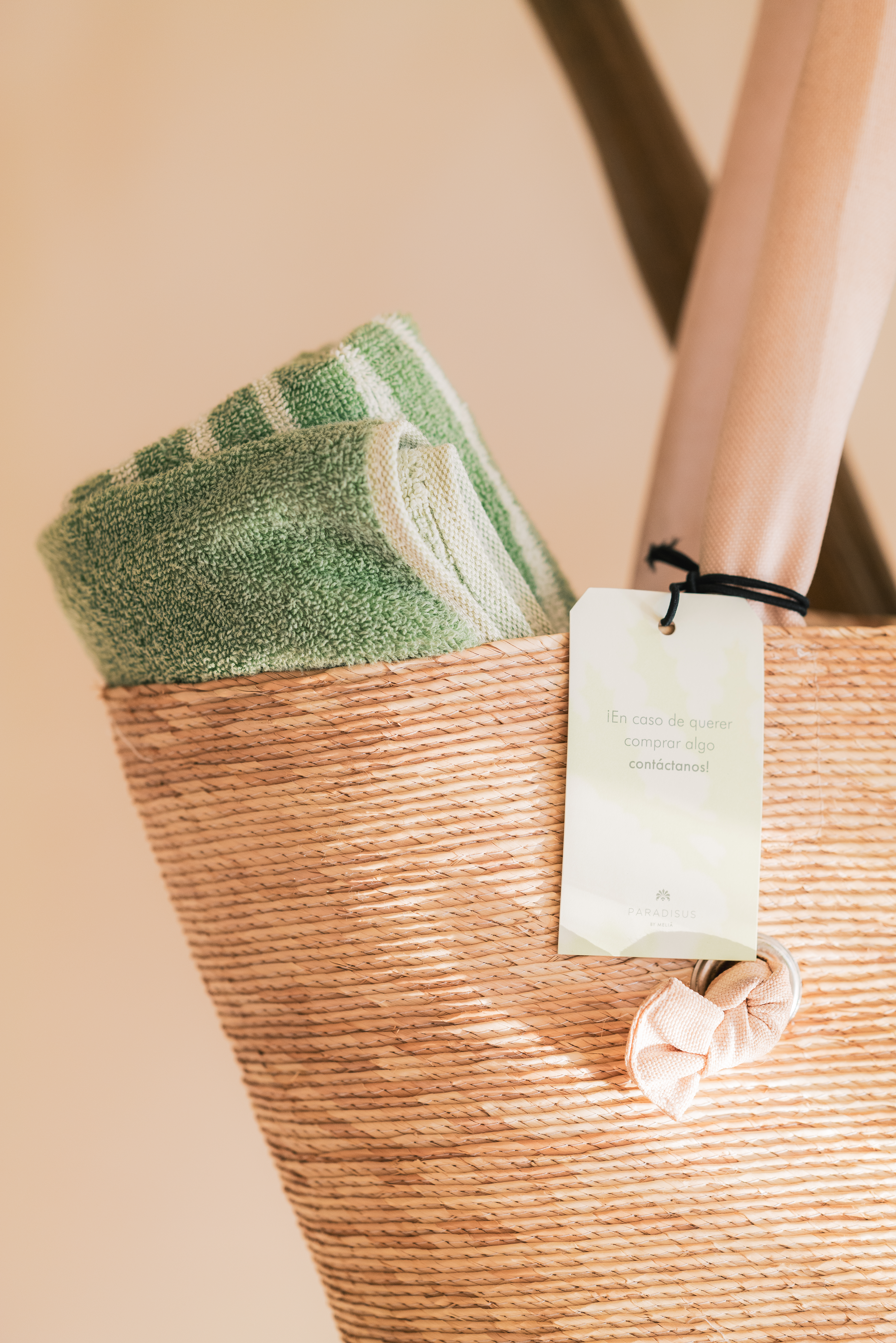 Straw beach bag with green striped towel and Paradisus hotel tag.