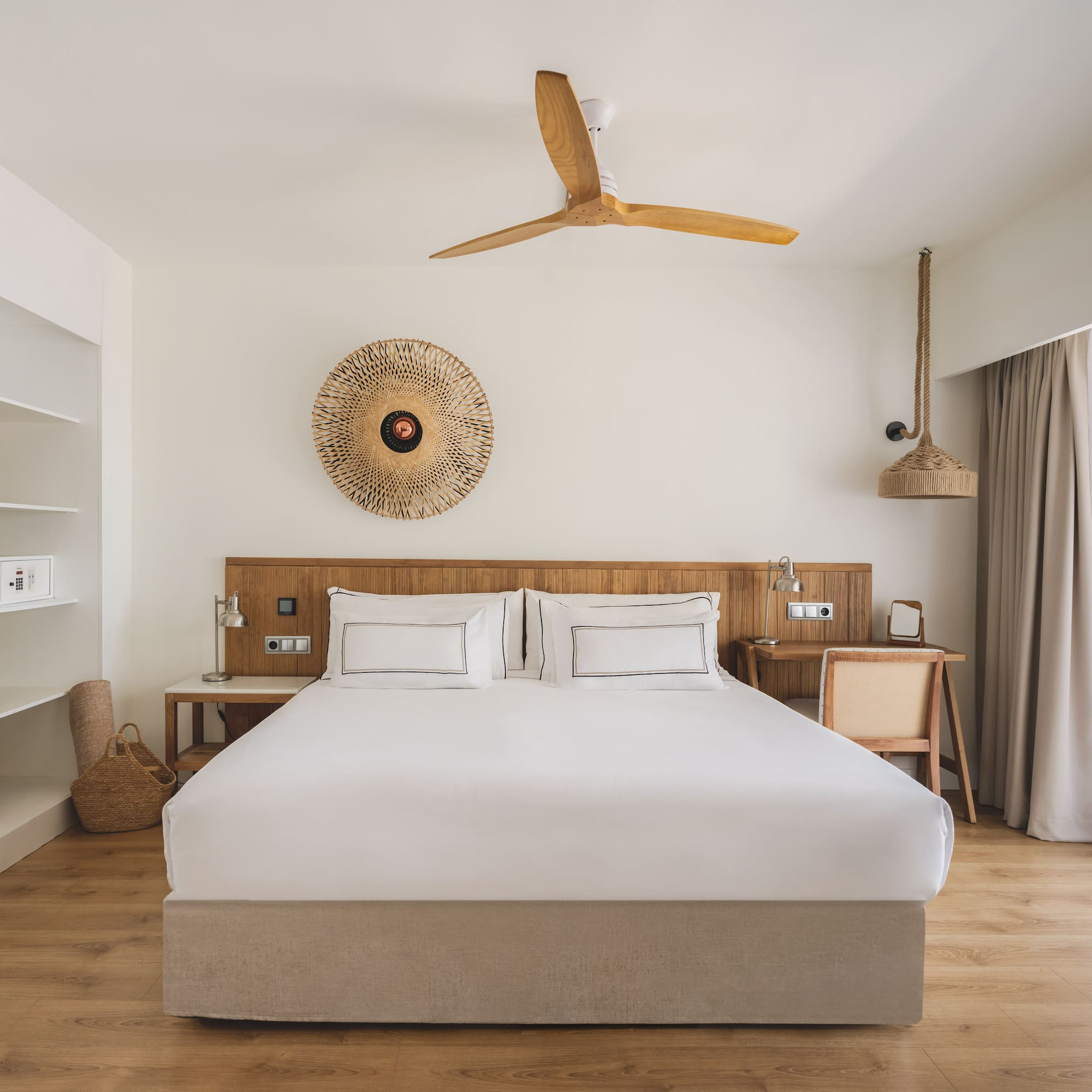 Hotel bedroom with king bed, wooden accents, closet, ceiling fan, and natural decor.