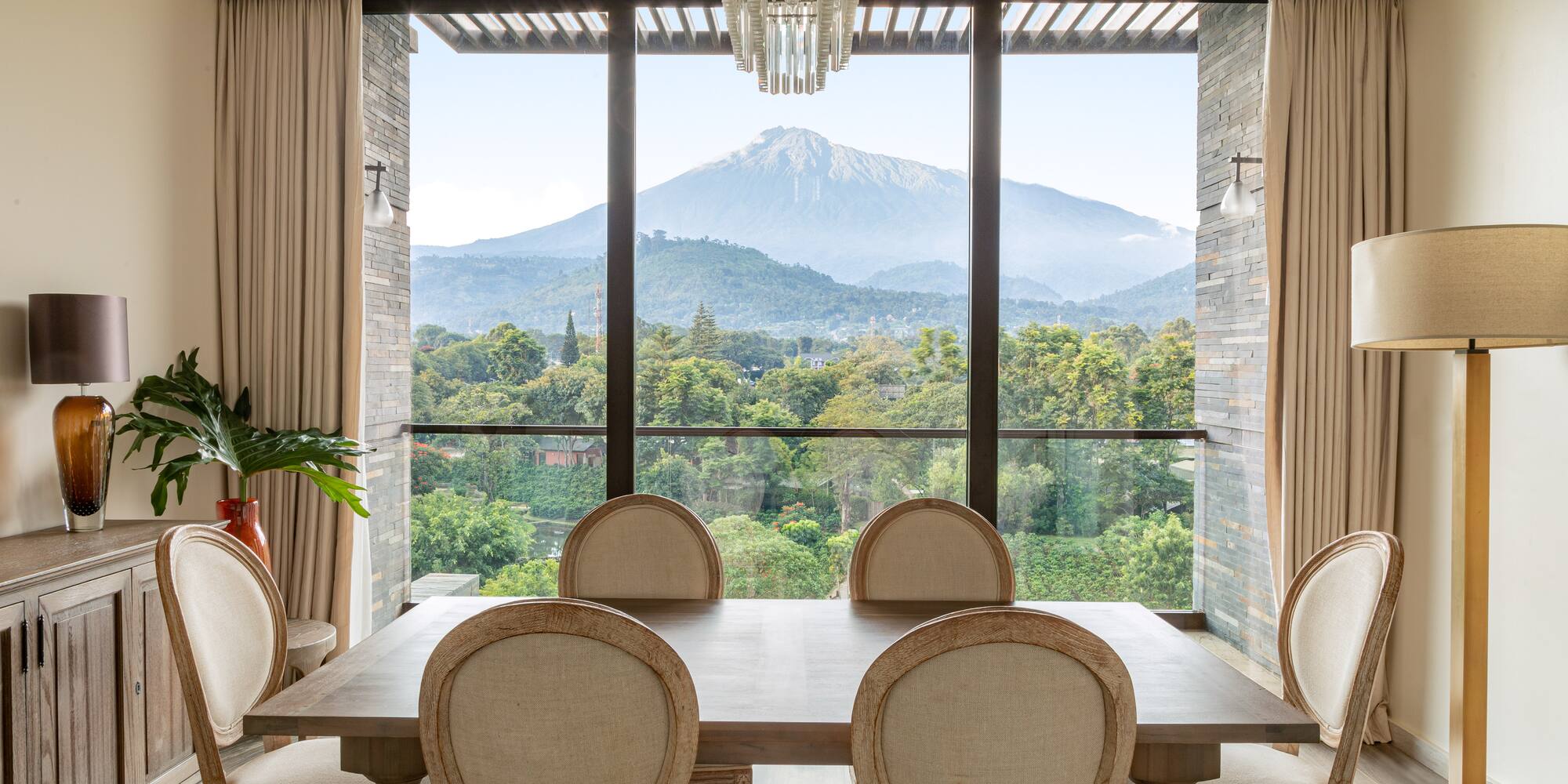 a room with a table and chairs and a view of a mountain