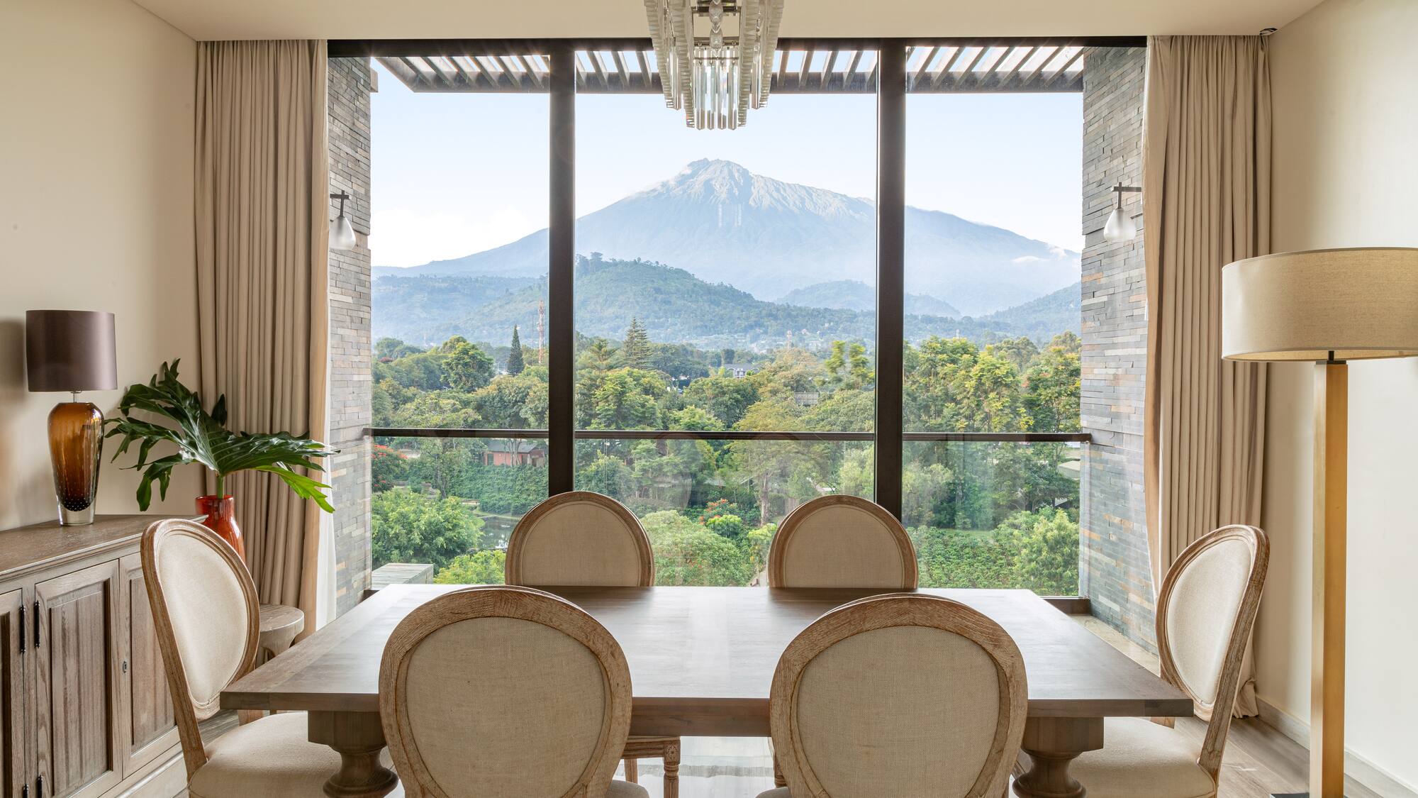 a room with a table and chairs and a view of a mountain