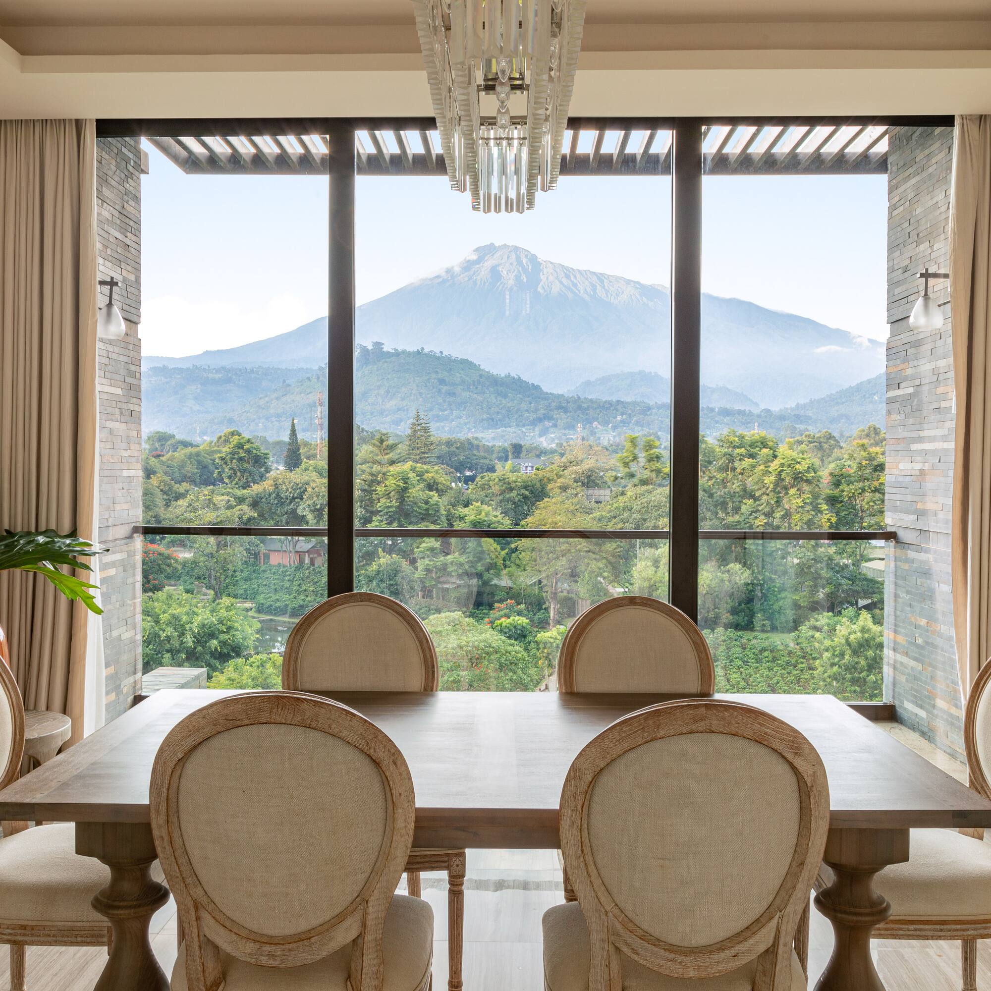 a room with a table and chairs and a view of a mountain