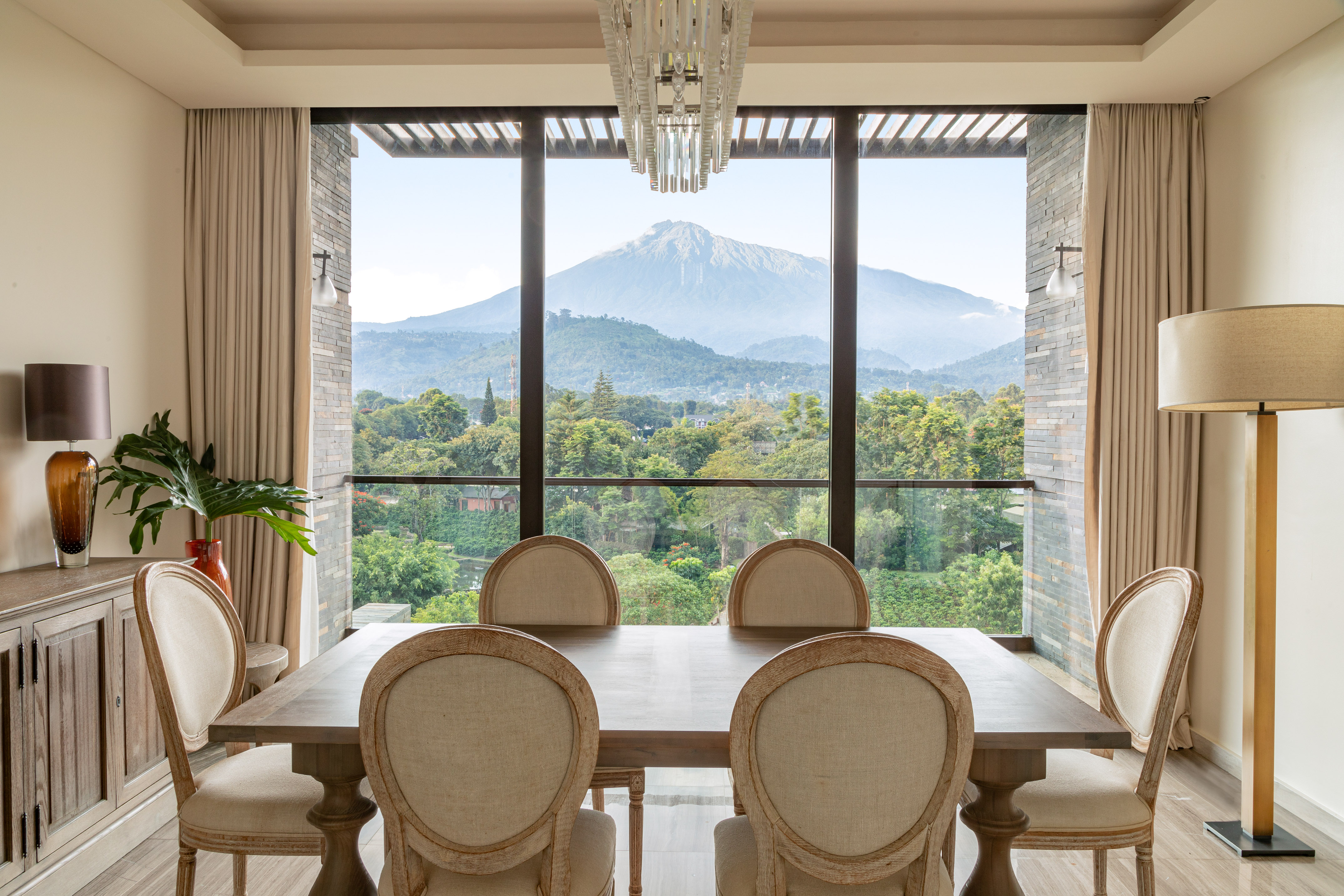 Elegant dining room with wooden table, upholstered chairs, and stunning mountain forest view.