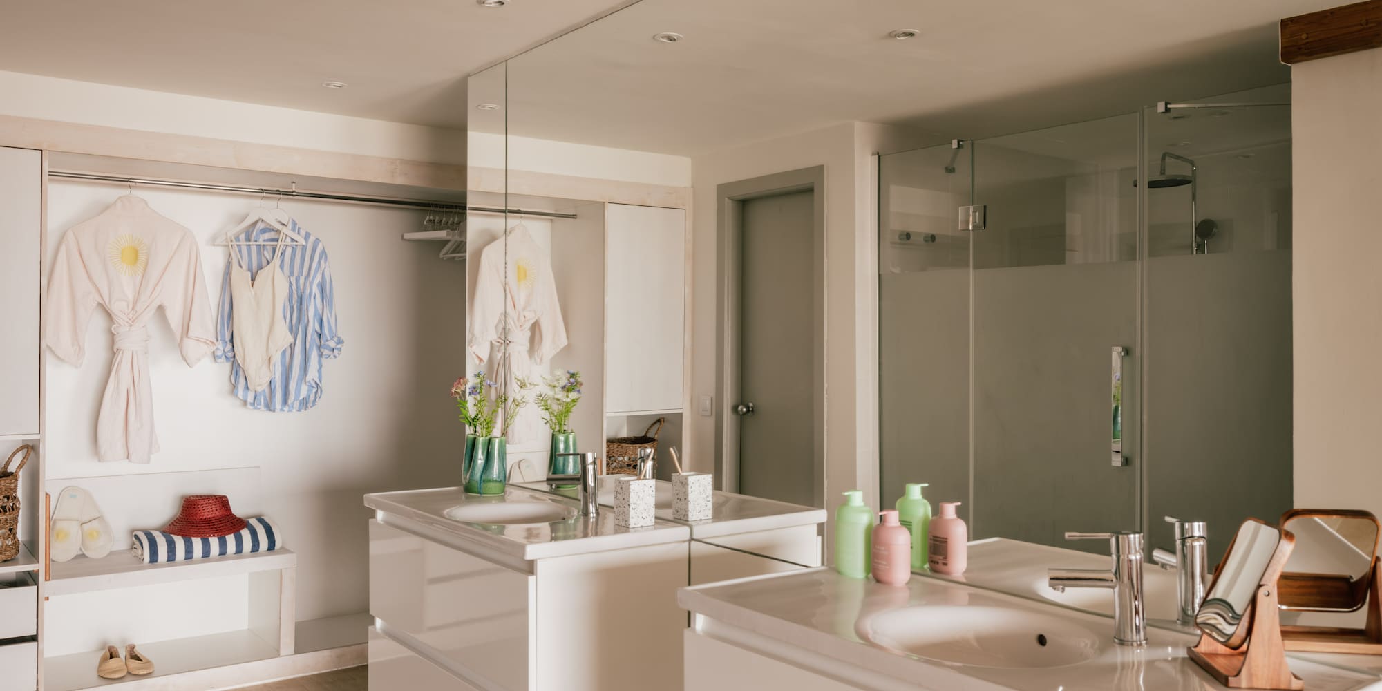 Modern bathroom with twin vanities, walk-in shower, and open closet area.