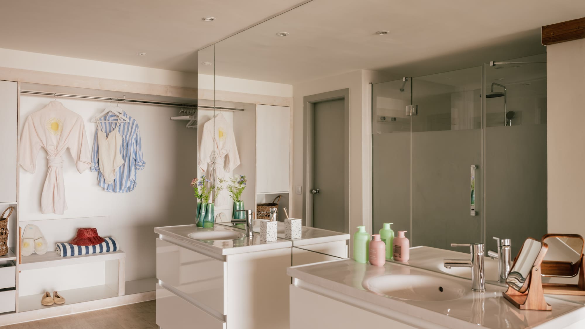 Modern bathroom with twin vanities, walk-in shower, and open closet area.