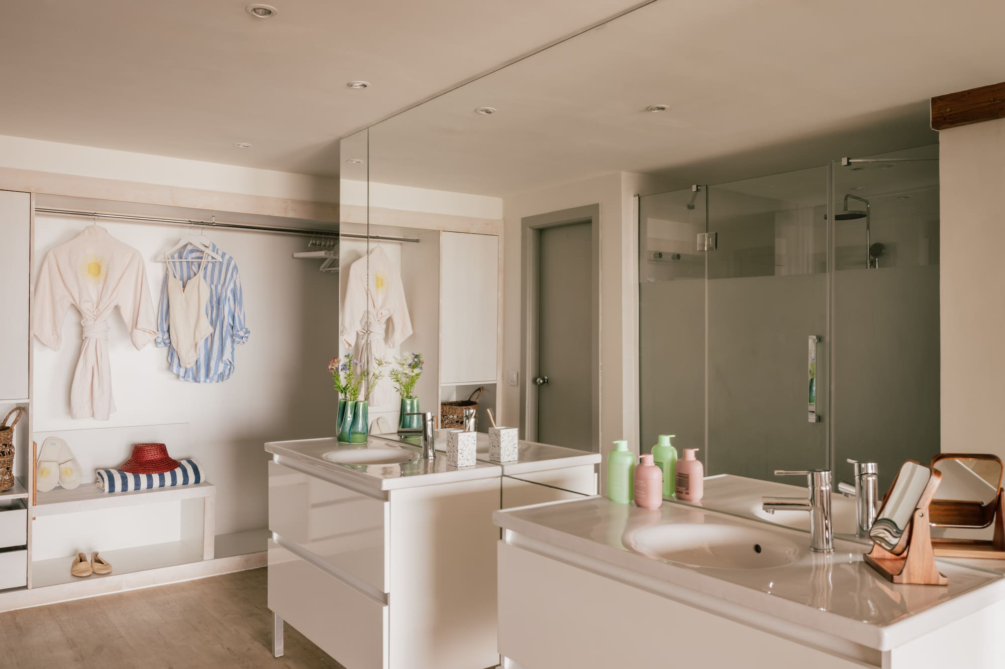 Modern bathroom with twin vanities, walk-in shower, and open closet area.