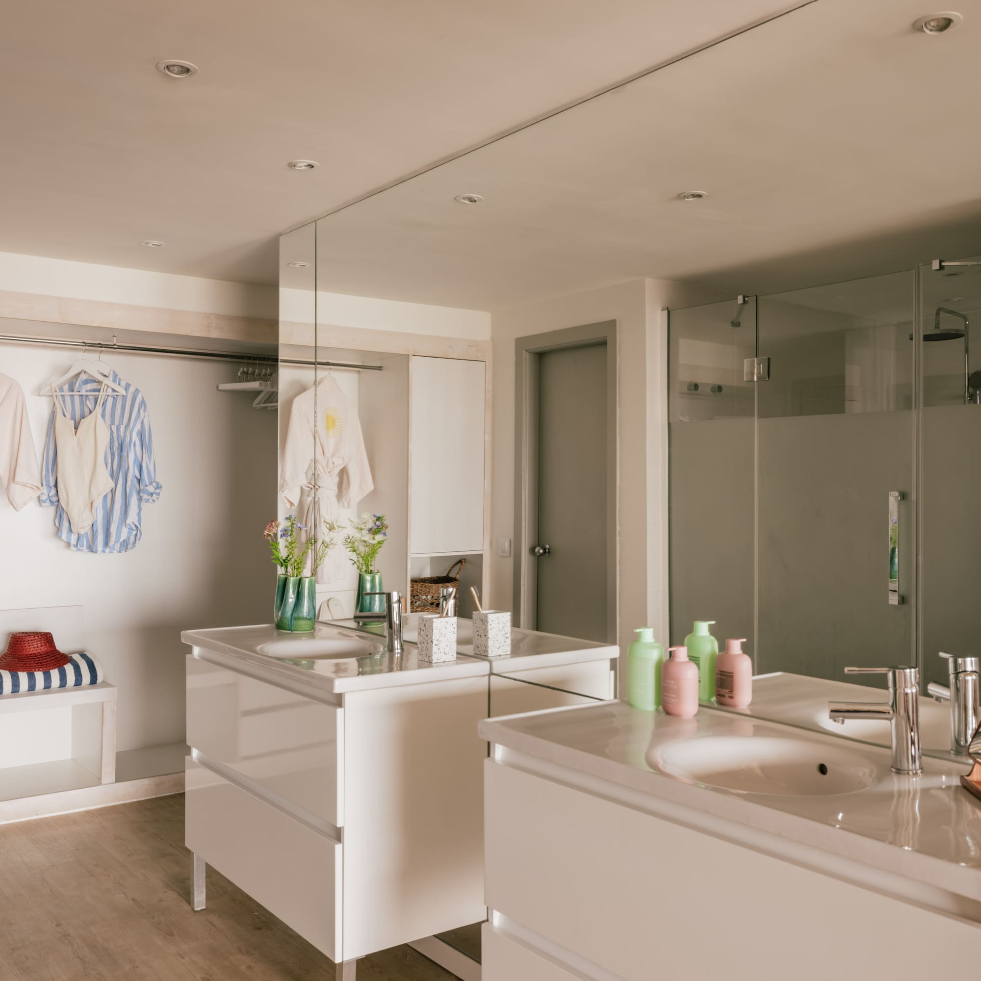 Modern bathroom with twin vanities, walk-in shower, and open closet area.