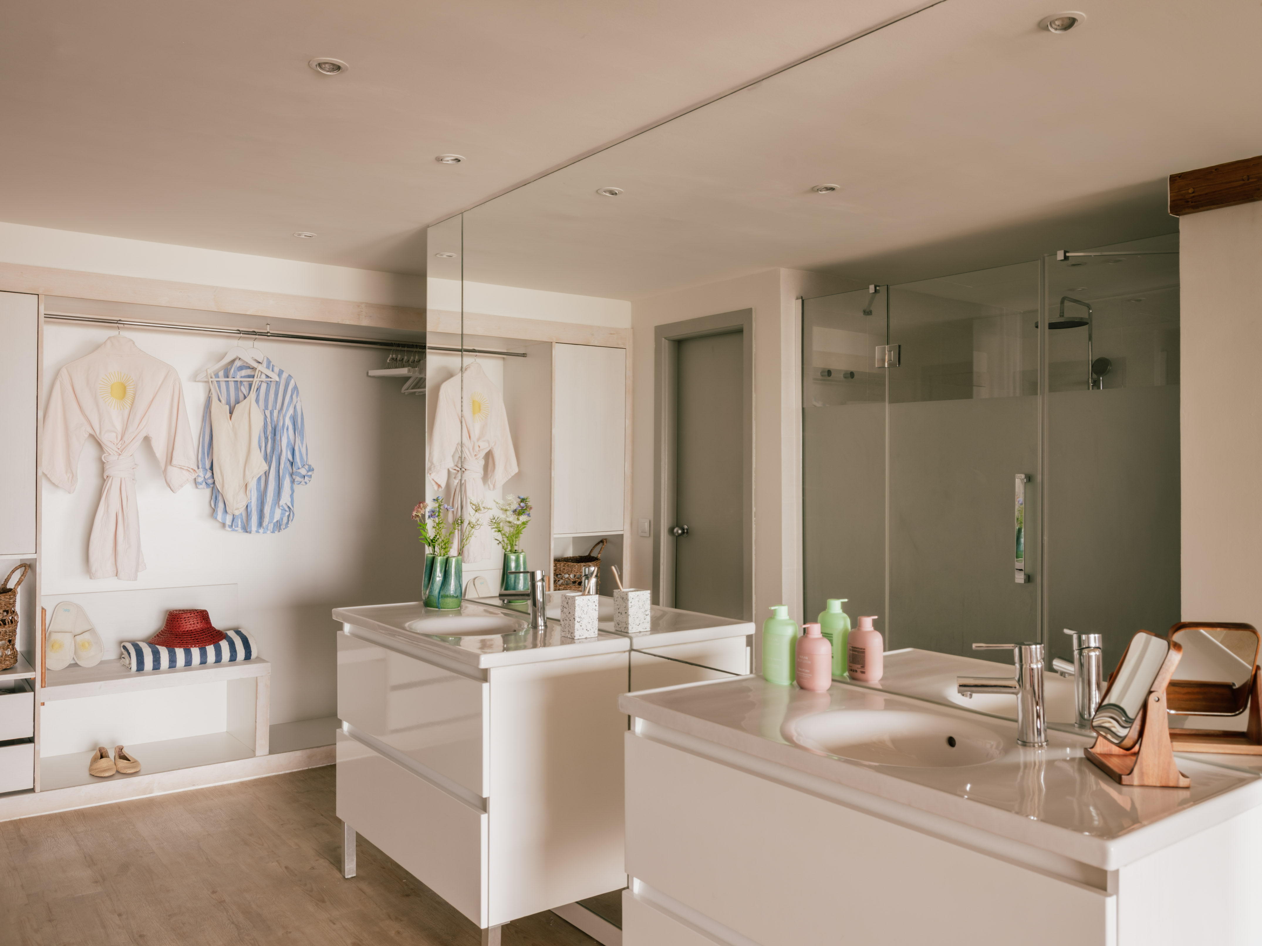Modern bathroom with twin vanities, walk-in shower, and open closet area.