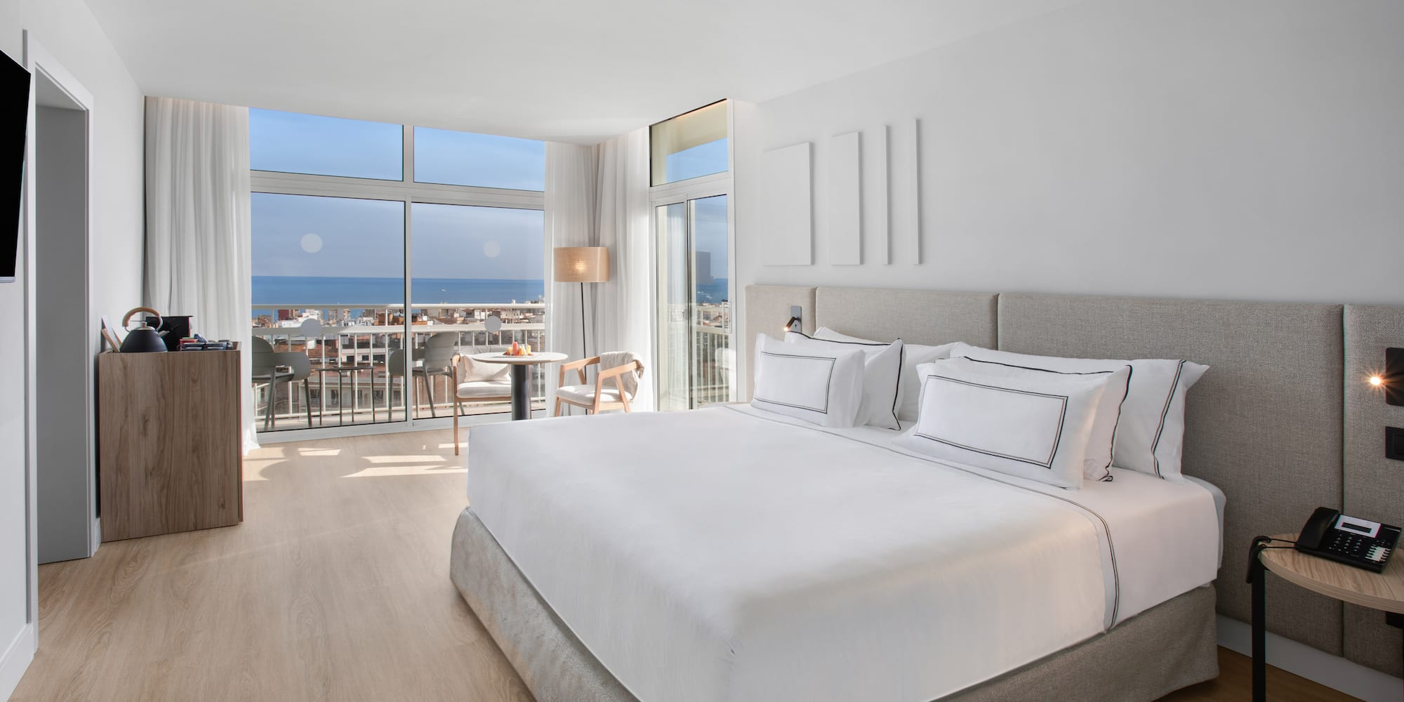 a bedroom with a large bed and a balcony overlooking the ocean