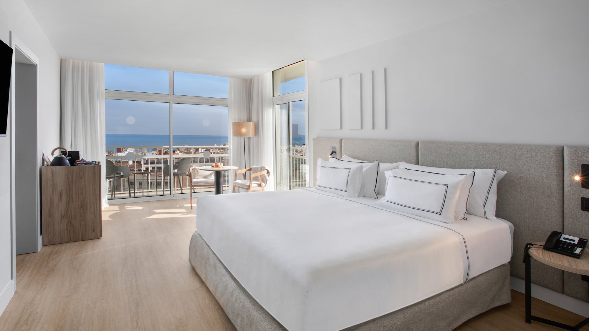 a bedroom with a large bed and a balcony overlooking the ocean
