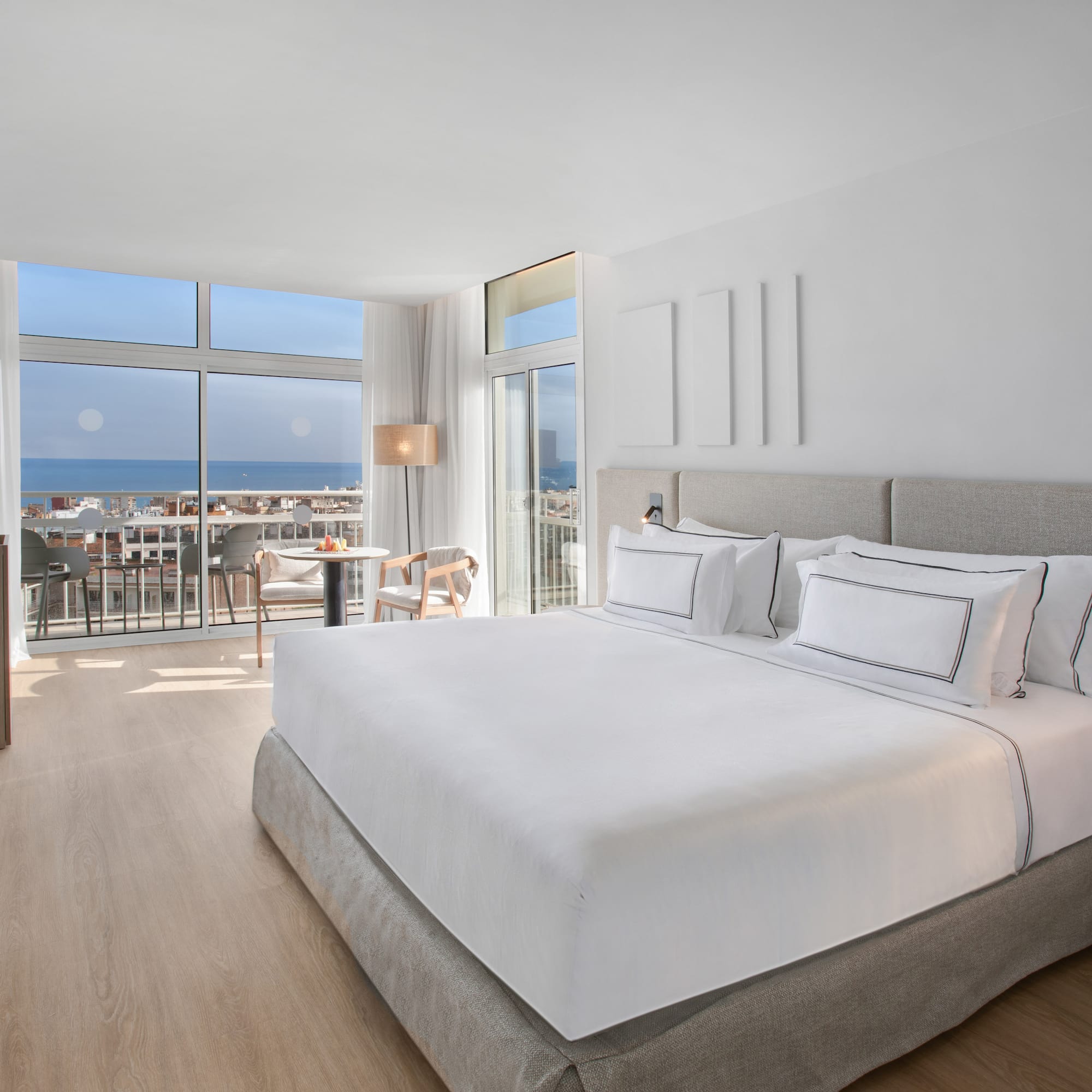 a bedroom with a large bed and a balcony overlooking the ocean