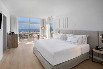 a bedroom with a large bed and a balcony overlooking the ocean