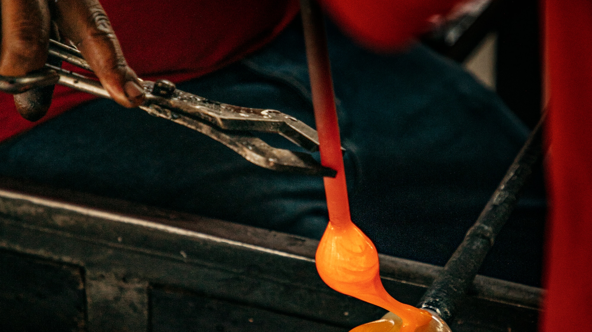 a person holding tongs over a piece of glass