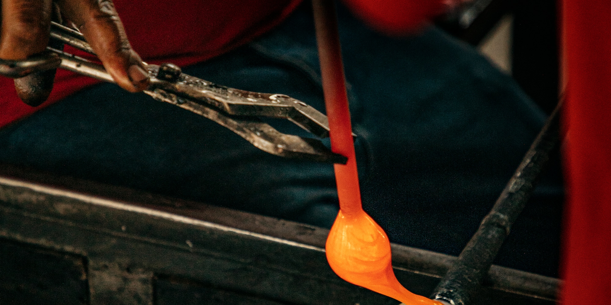 a person holding tongs over a piece of glass