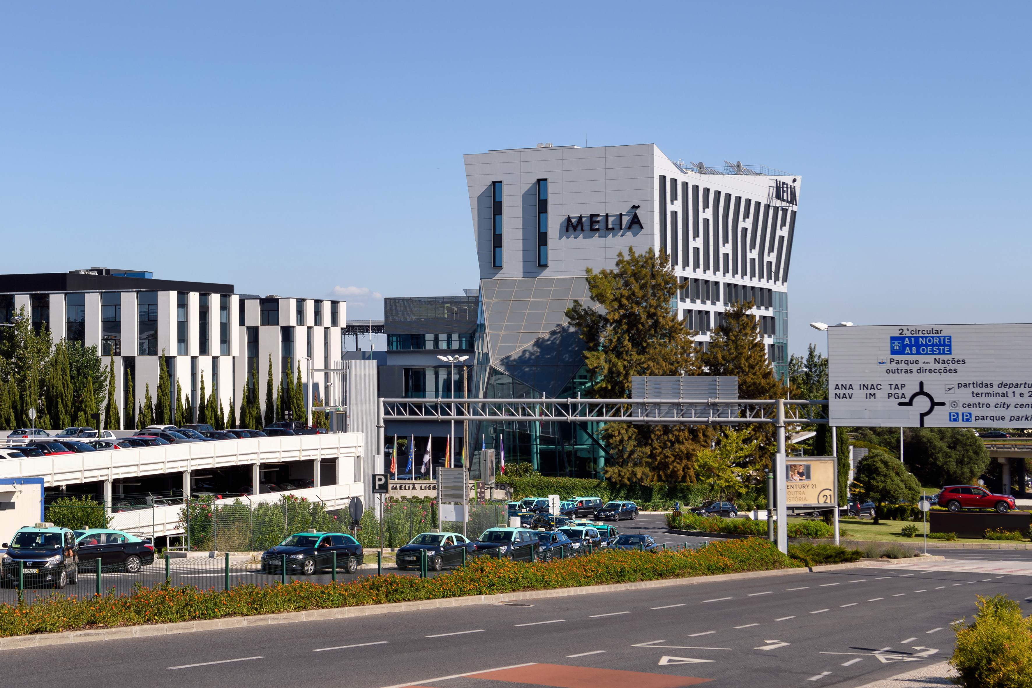 Modern Melia Hotel in Lisbon with highway, cars, and airport signs.