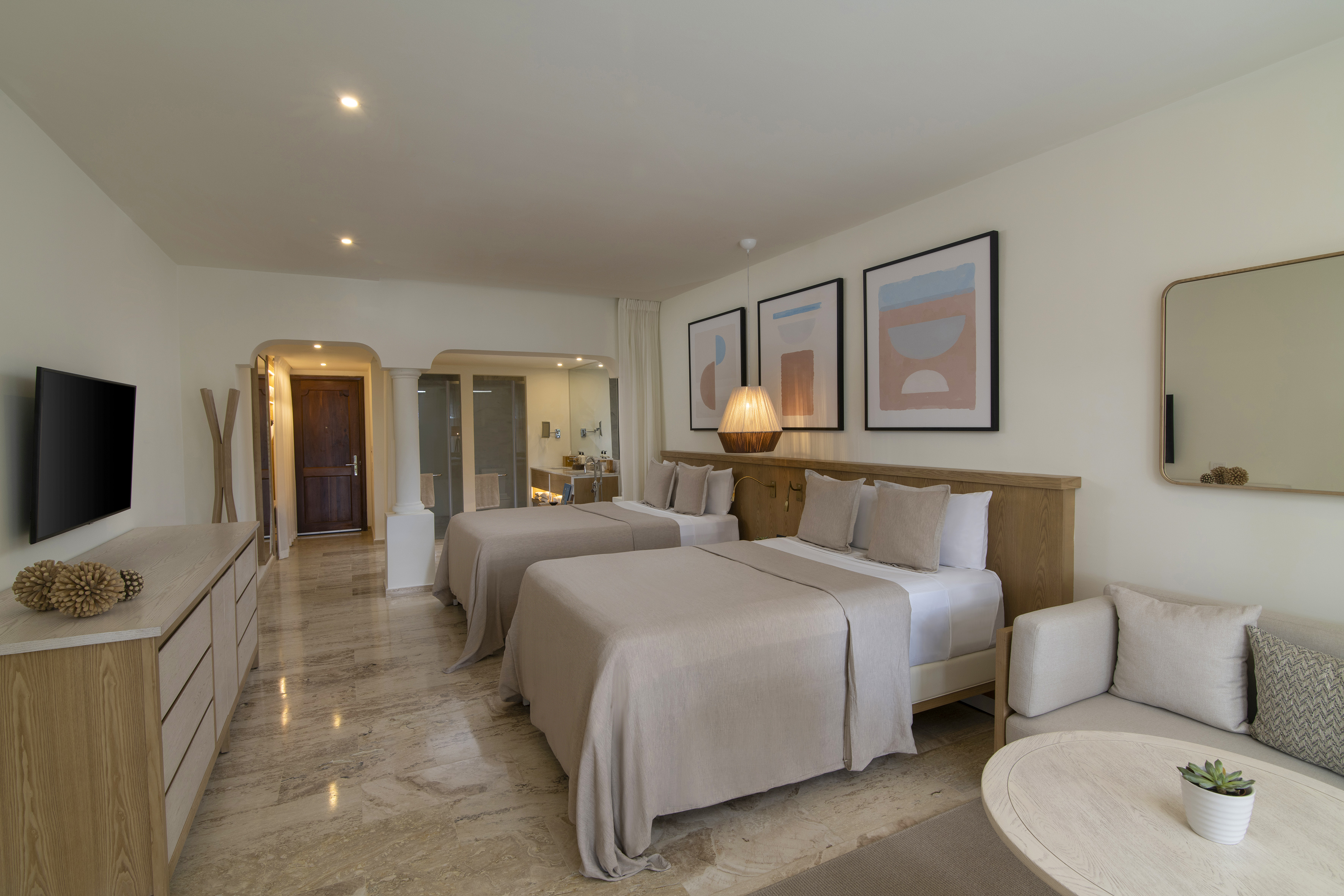 Modern hotel room with two beds, neutral tones, marble floor, and contemporary art.
