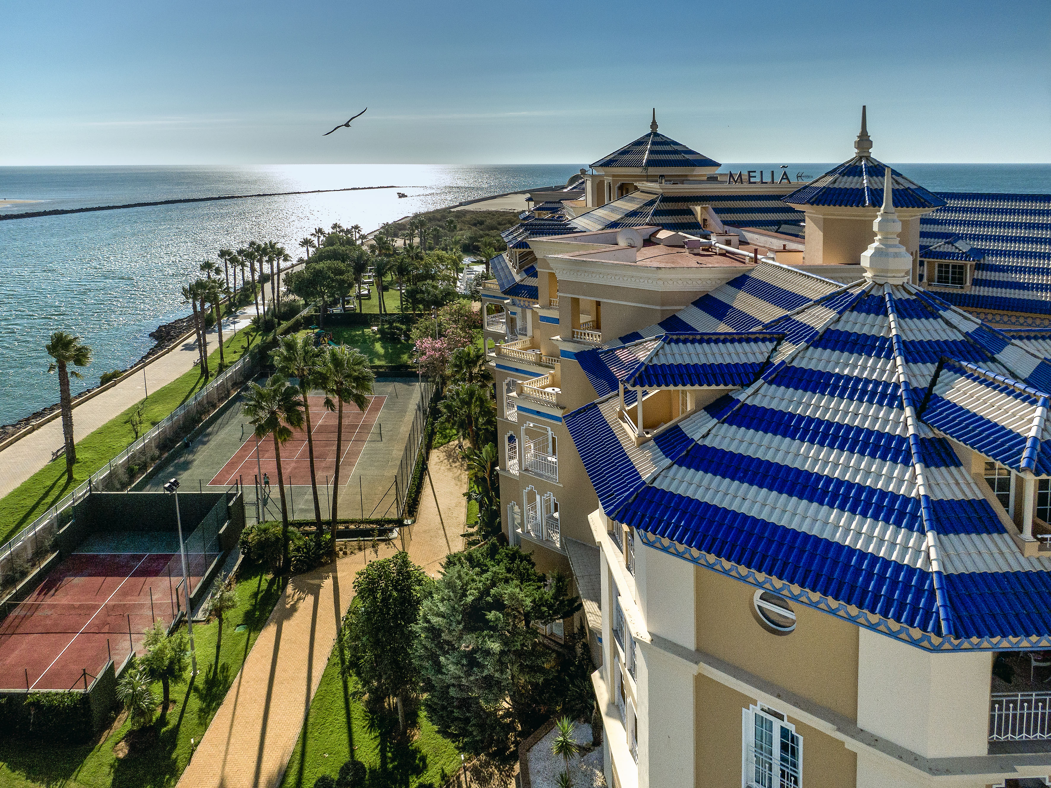 Meliá hotel, oceanfront resort with blue roofs, palm trees, and tennis courts.