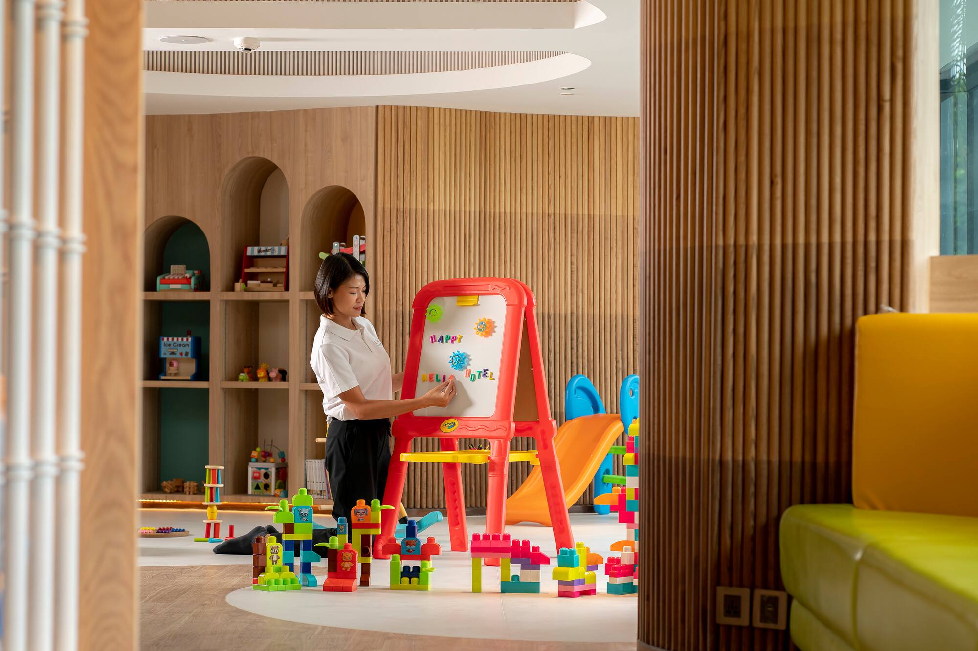 Staff at easel in a colorful hotel kids' play area with building blocks.