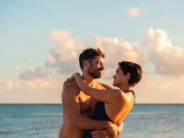 a man and woman hugging on a beach