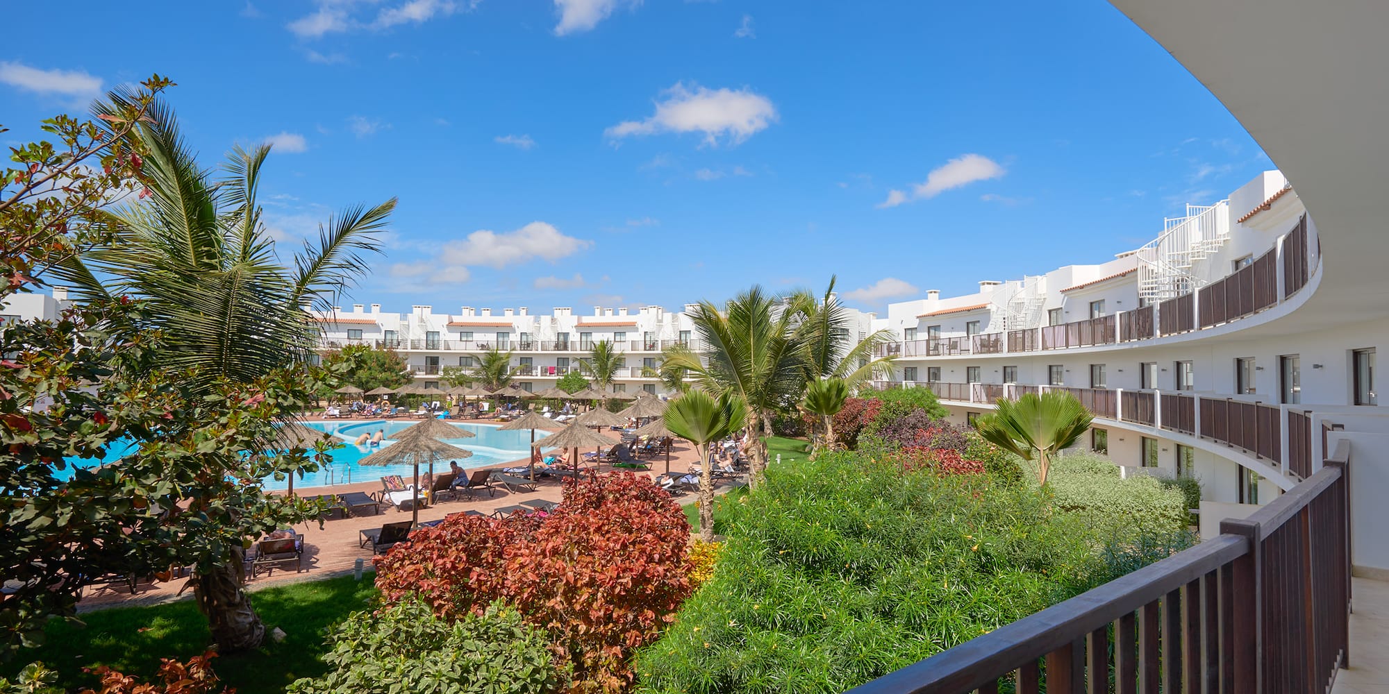 a pool and trees in front of a hotel
