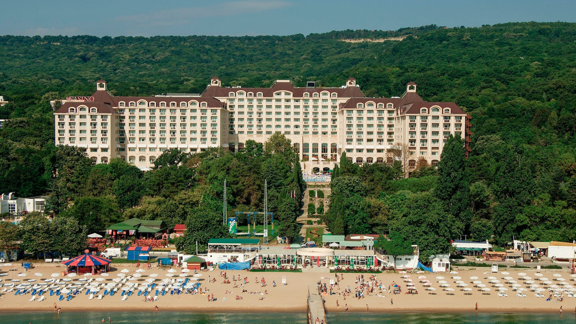 a large building with many windows and a beach and trees