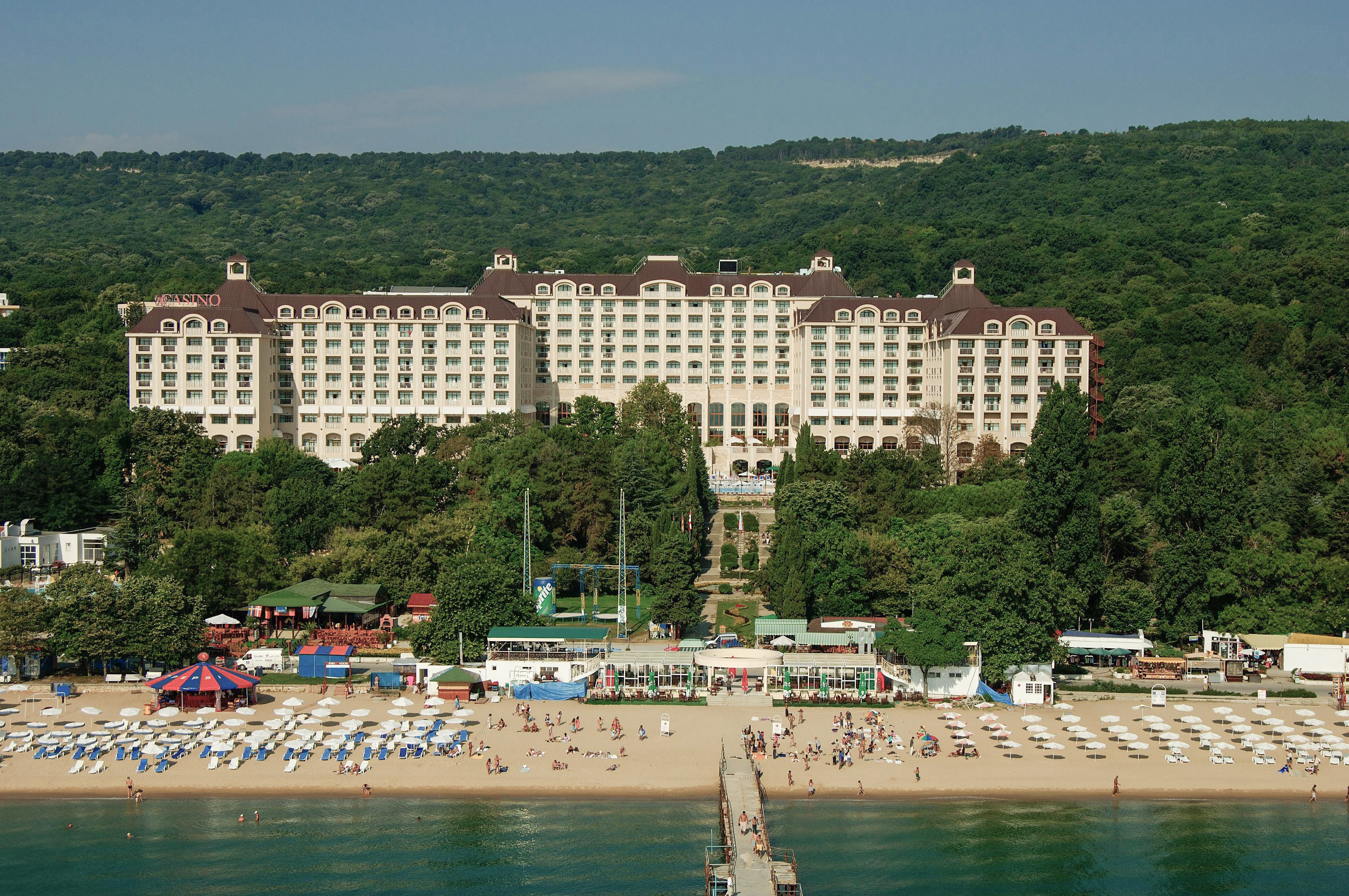 a large building with many windows and a beach and trees