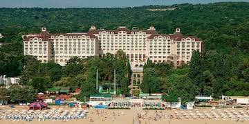 a large building with many windows and a beach and trees