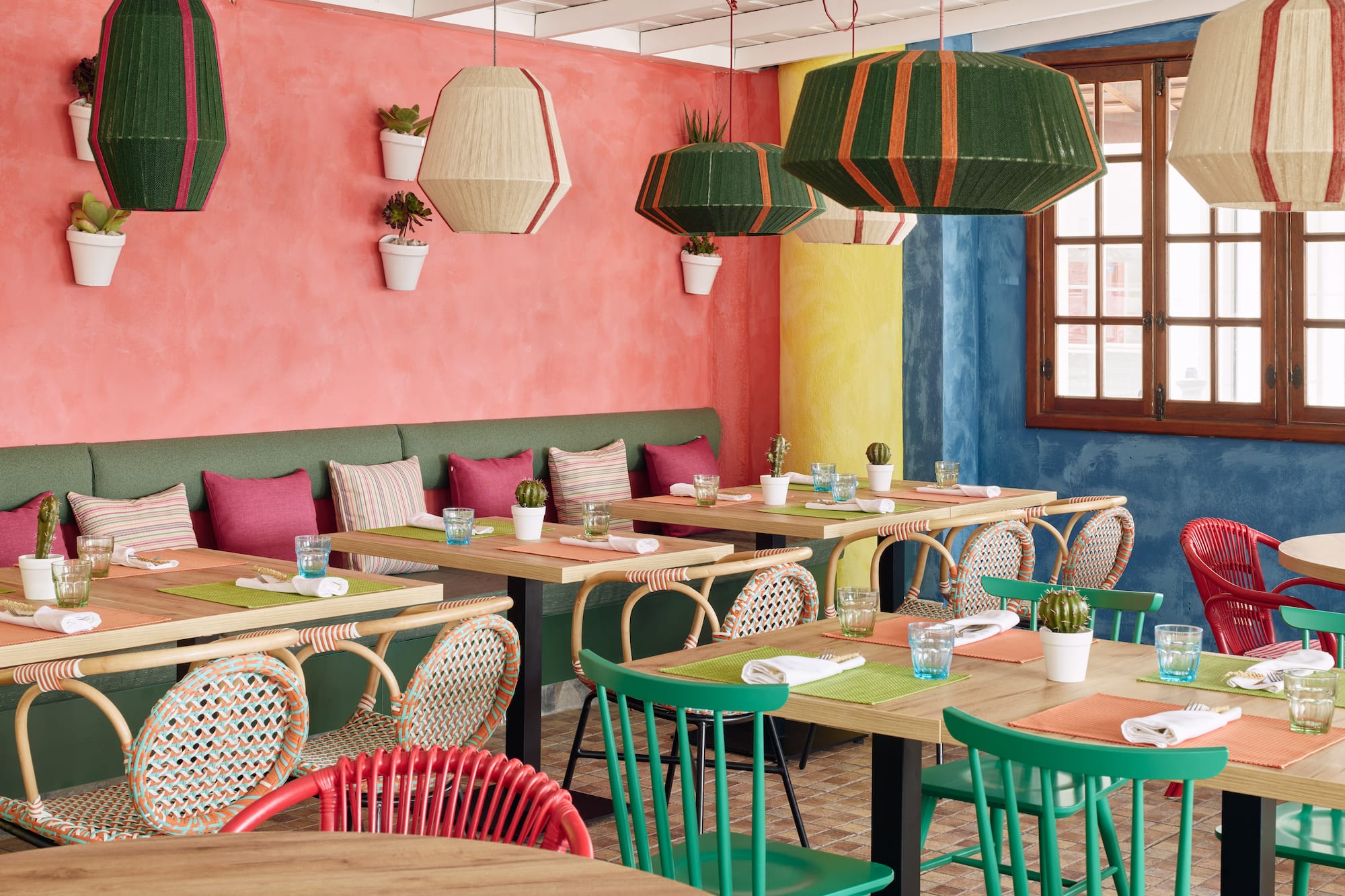 Vibrant colorful restaurant interior with diverse seating, lively decor, and woven lamps.