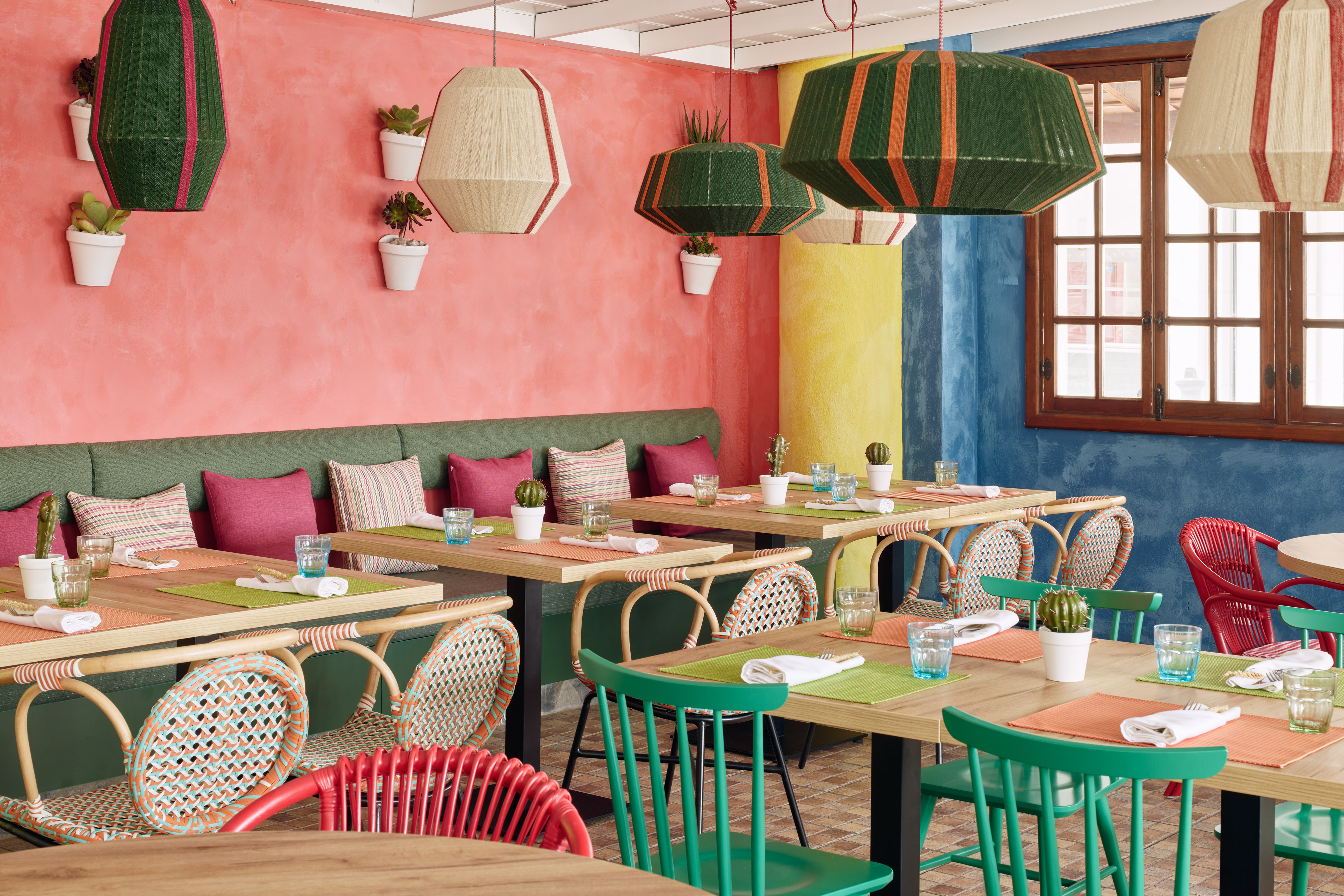 Vibrant colorful restaurant interior with diverse seating, lively decor, and woven lamps.
