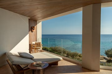 a lounge chair and a table overlooking the ocean
