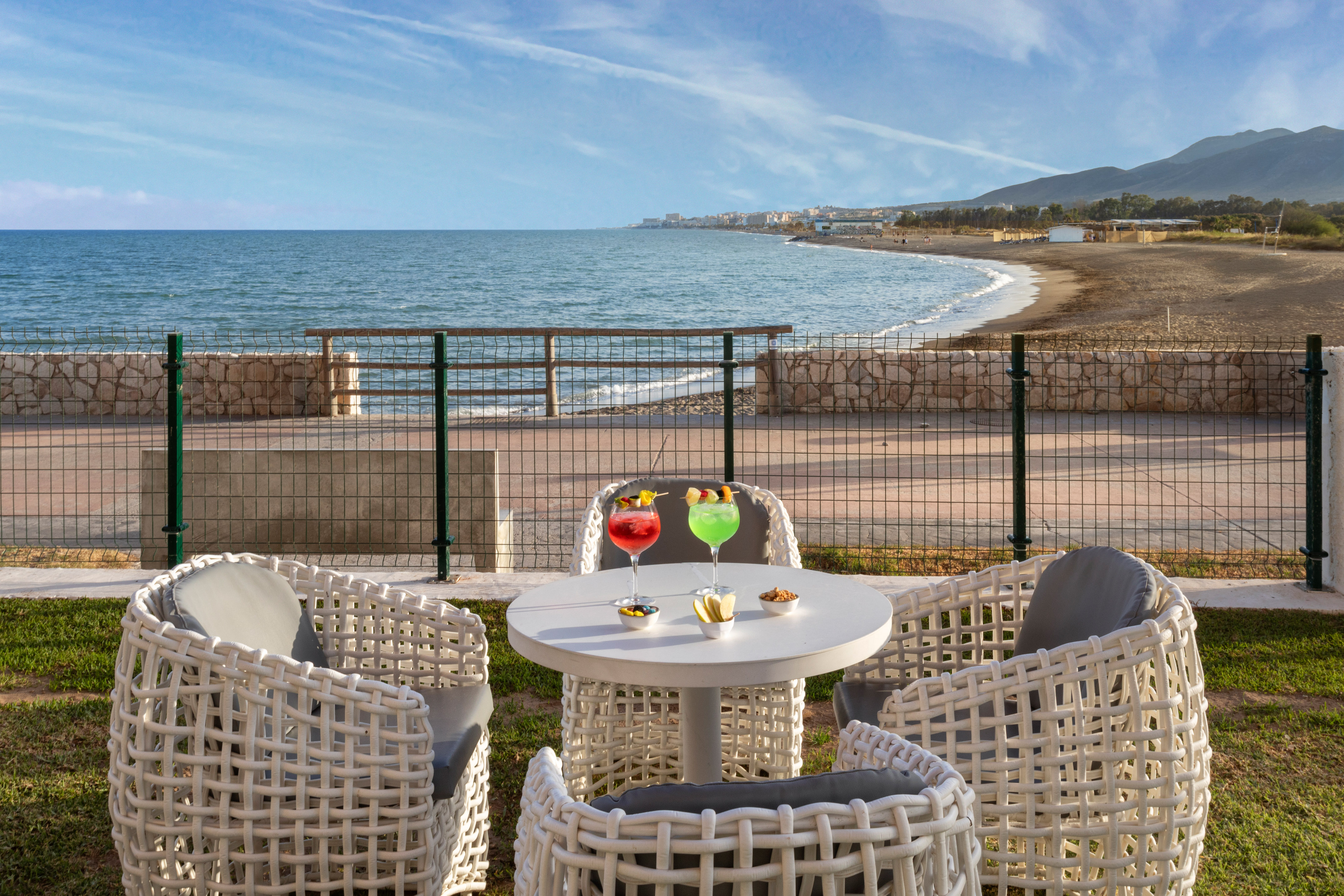 Two cocktails on a table at a beachfront patio overlooking the sea.