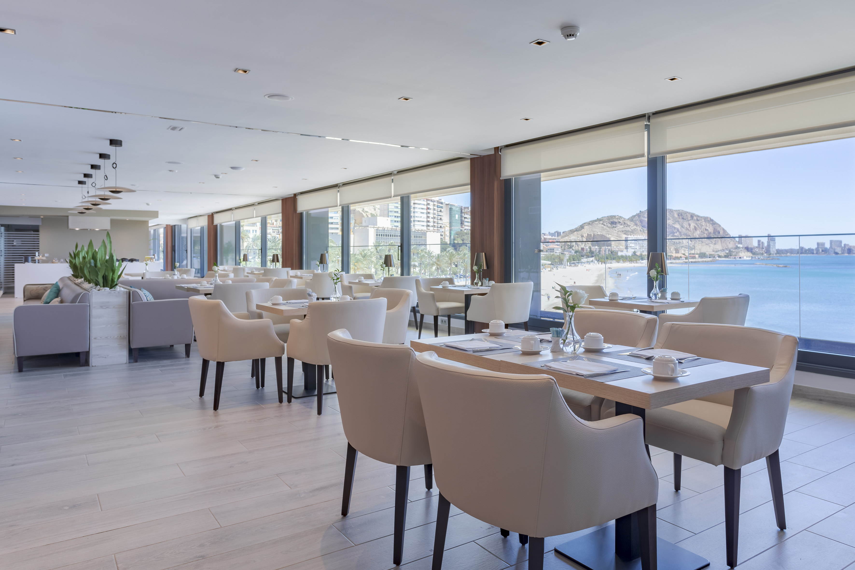 Comedor de hotel moderno con vista panorámica a la playa y al mar.