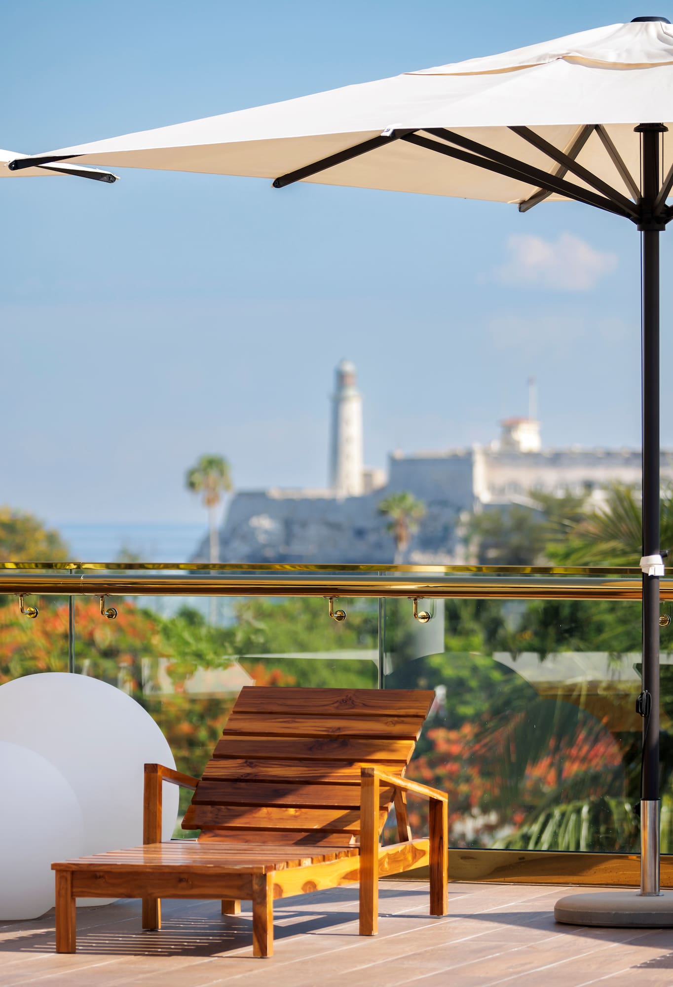 a chair on a balcony with a white umbrella and trees