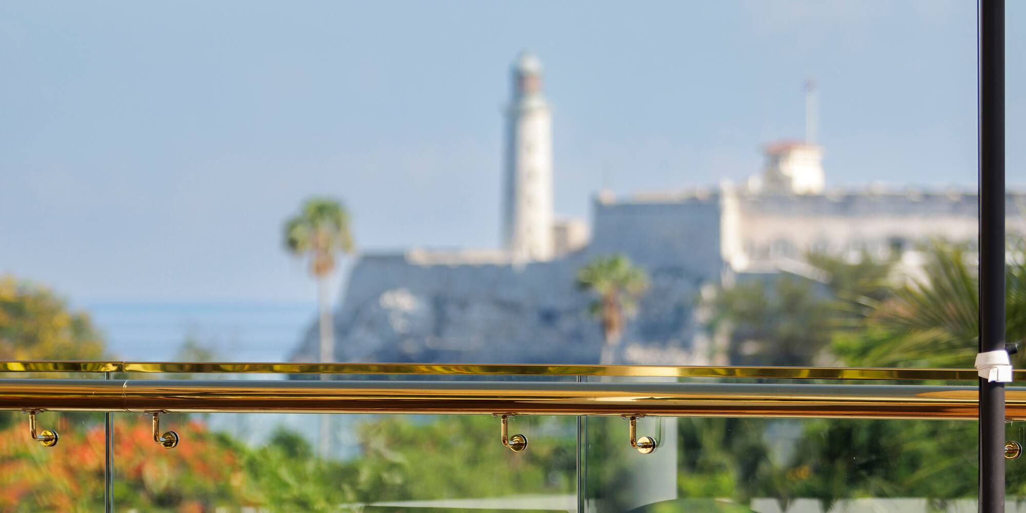 a chair on a balcony with a white umbrella and trees