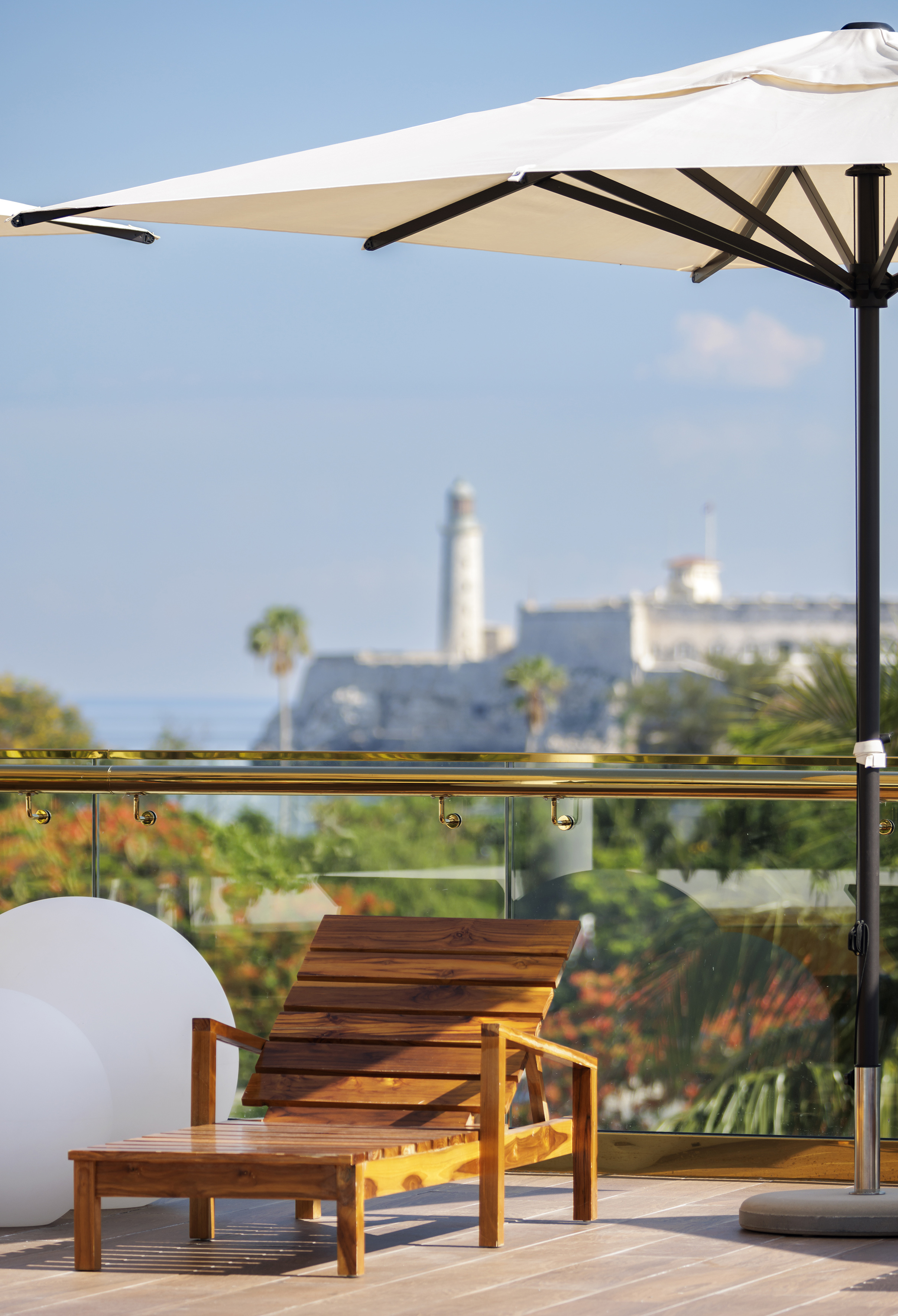 a chair on a balcony with a white umbrella and trees